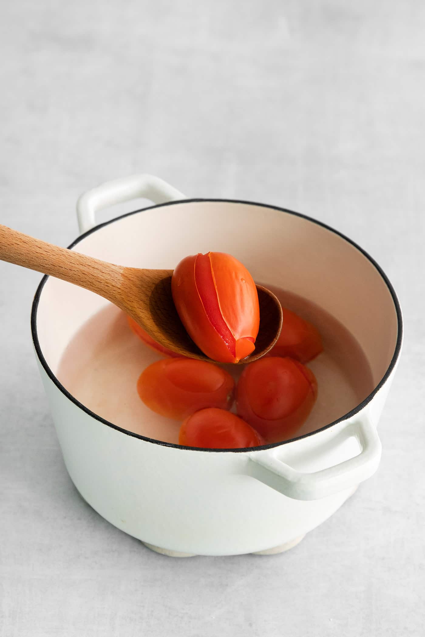 Made with juicy tomatoes, celery, onion, and green pepper these Chili Stewed Tomatoes make a mouthwatering side dish. A spoon pulling a roma tomato from a pot of water
