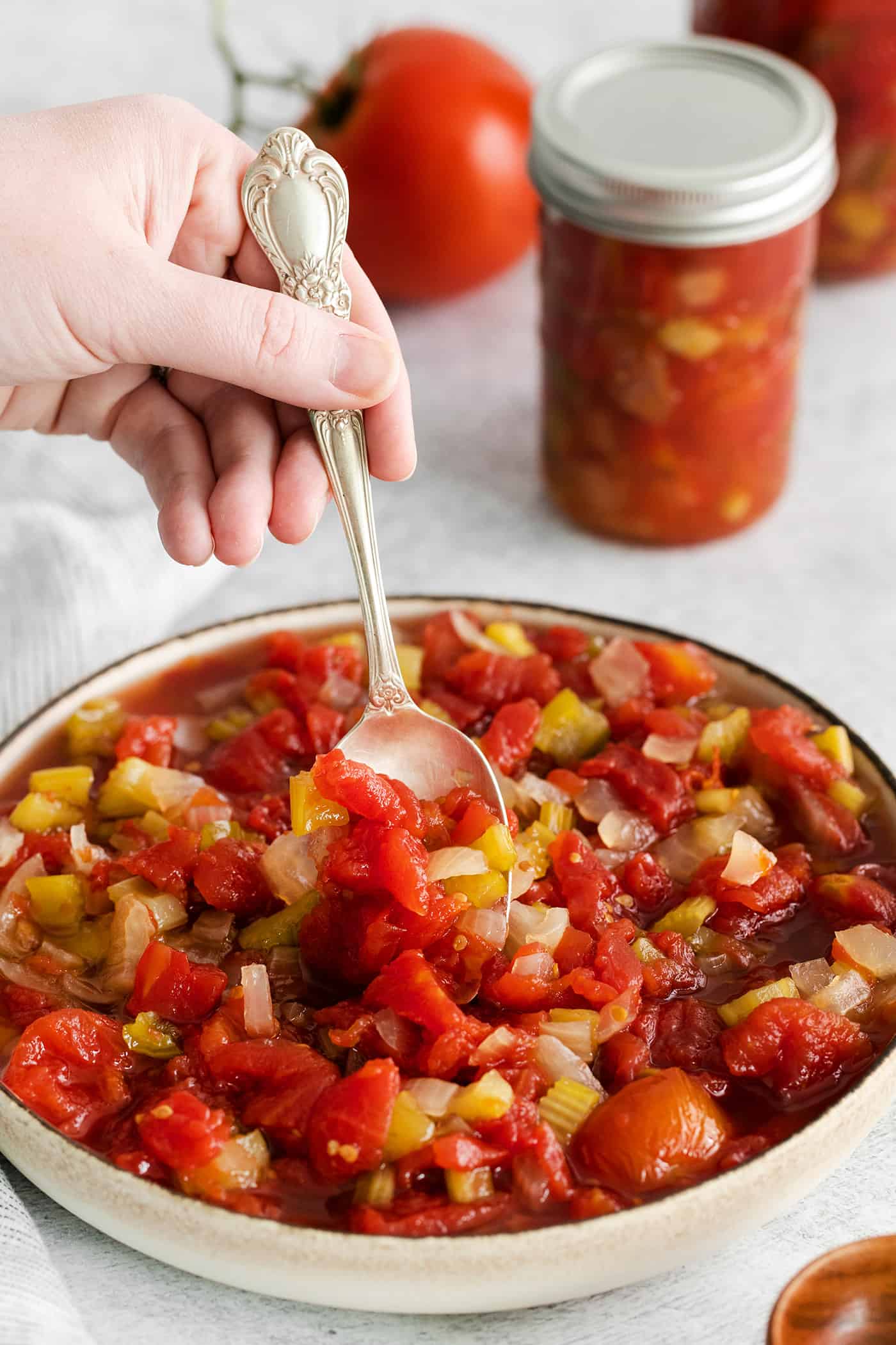 Made with juicy tomatoes, celery, onion, and green pepper these Chili Stewed Tomatoes make a mouthwatering side dish. A spoon stirring chili stewed tomatoes