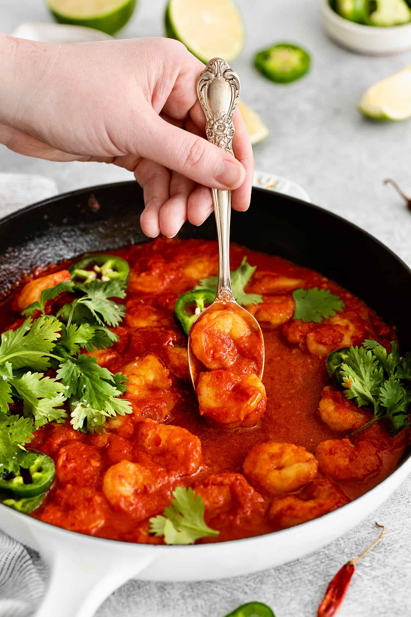 Camarones a la Diabla is a classic Mexican seafood dish that features fresh shrimp, dried chiles, and ripe tomatoes. Ready in 30 minutes! A fork grabbing a diablo shrimp from the skillet