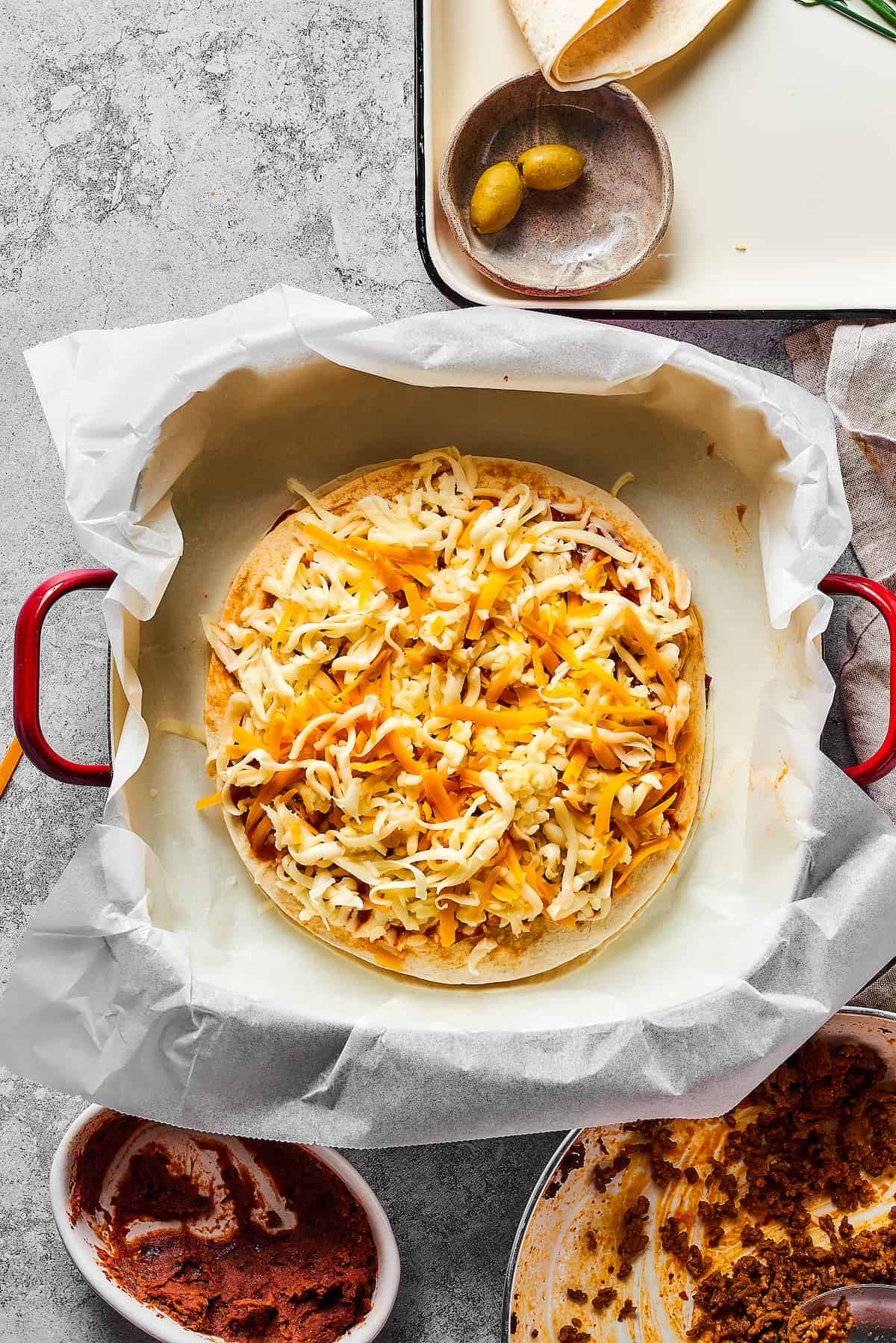 Made with taco meat, refried beans, and enchilada sauce layers with tortillas and cheese, Mexican Pizza is easy & tasty. Overhead view of a mexican pizza
