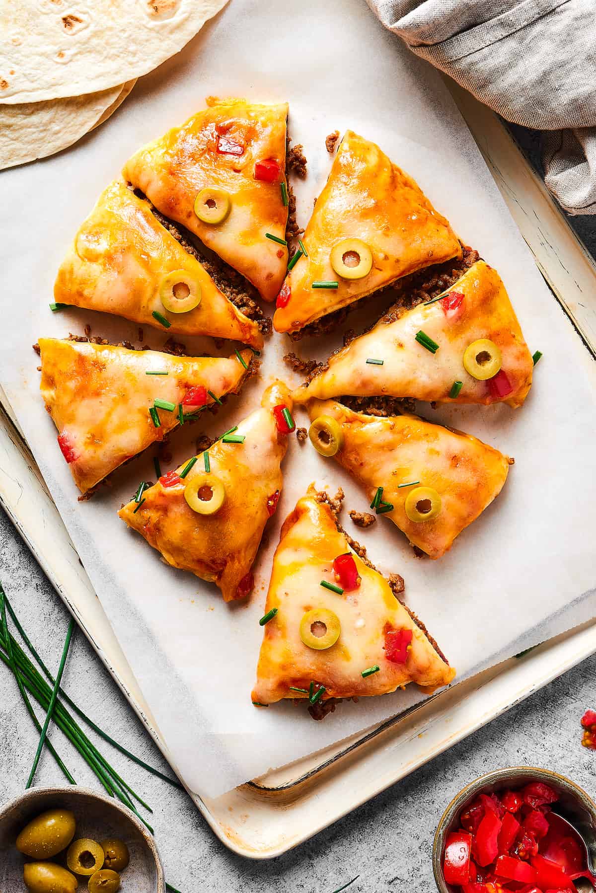 Made with taco meat, refried beans, and enchilada sauce layers with tortillas and cheese, Mexican Pizza is easy & tasty. Overhead view of a Mexican Pizza cut into triangles