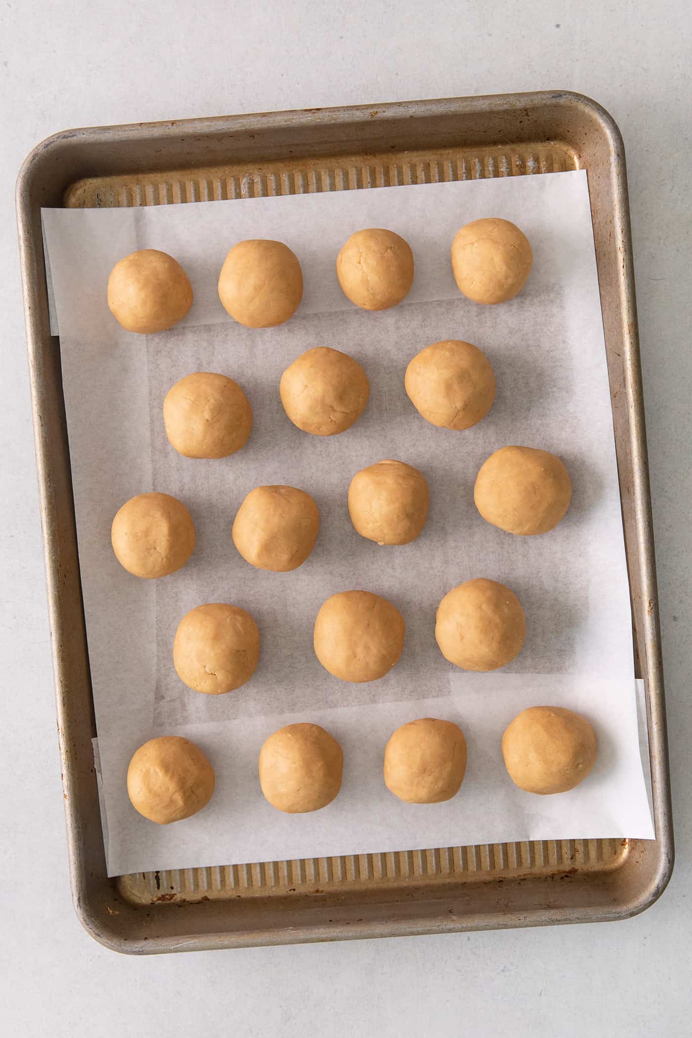 These Homemade Buckeyes feature creamy peanut butter balls dipped in rich, smooth semi-sweet chocolate. Just 7 ingredients! Peanut butter balls on a cookie sheet
