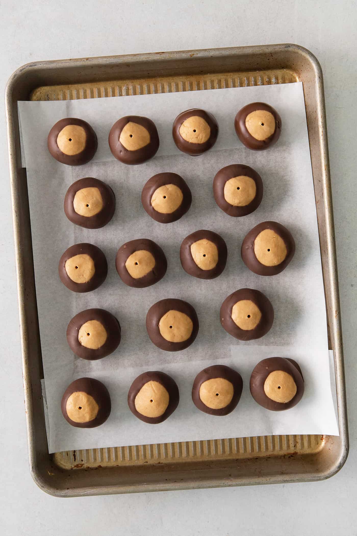 These Homemade Buckeyes feature creamy peanut butter balls dipped in rich, smooth semi-sweet chocolate. Just 7 ingredients! Overhead view of buckeye balls on a baking sheet