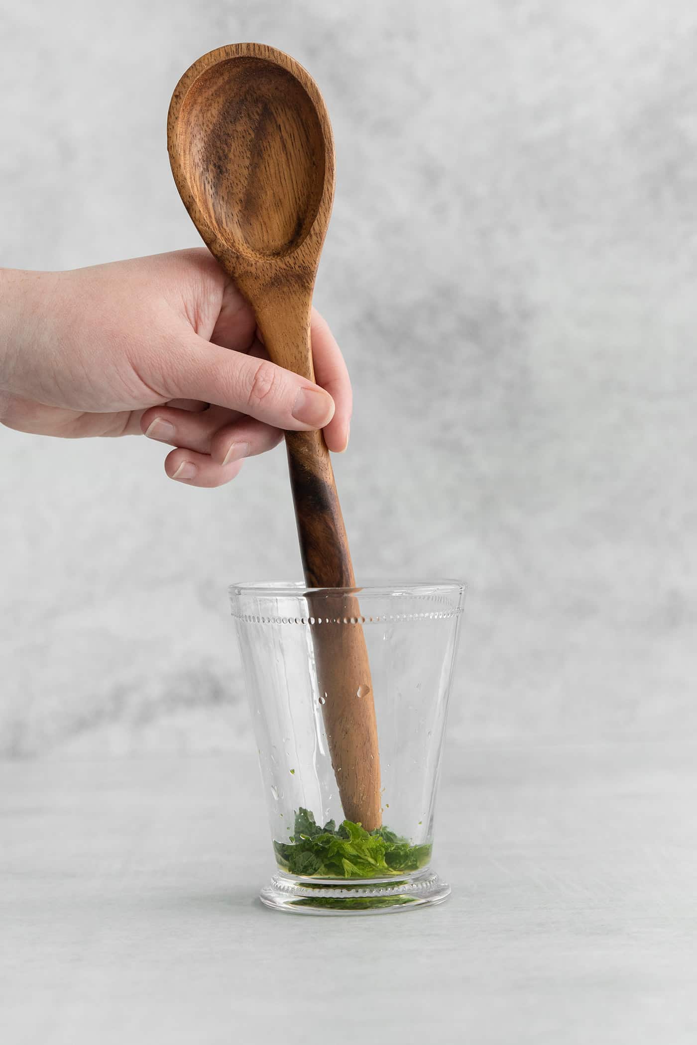 This classic Mint Julep is bright and refreshing, with fresh mint flavor and a hint of smoky bourbon. All you'll need is 3 ingredients! The end of a wooden spoon muddling mint in a glass