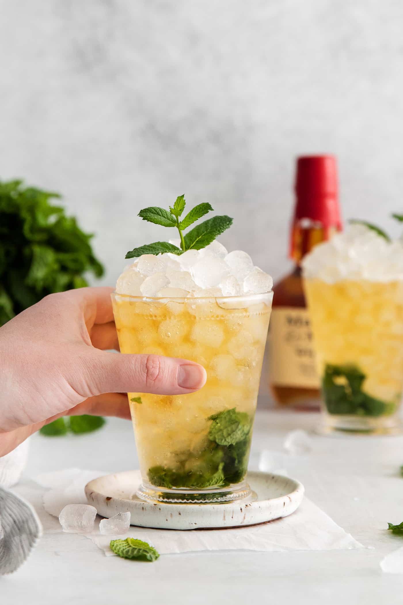 This classic Mint Julep is bright and refreshing, with fresh mint flavor and a hint of smoky bourbon. All you'll need is 3 ingredients! A hand grabbing a mint julep cocktail