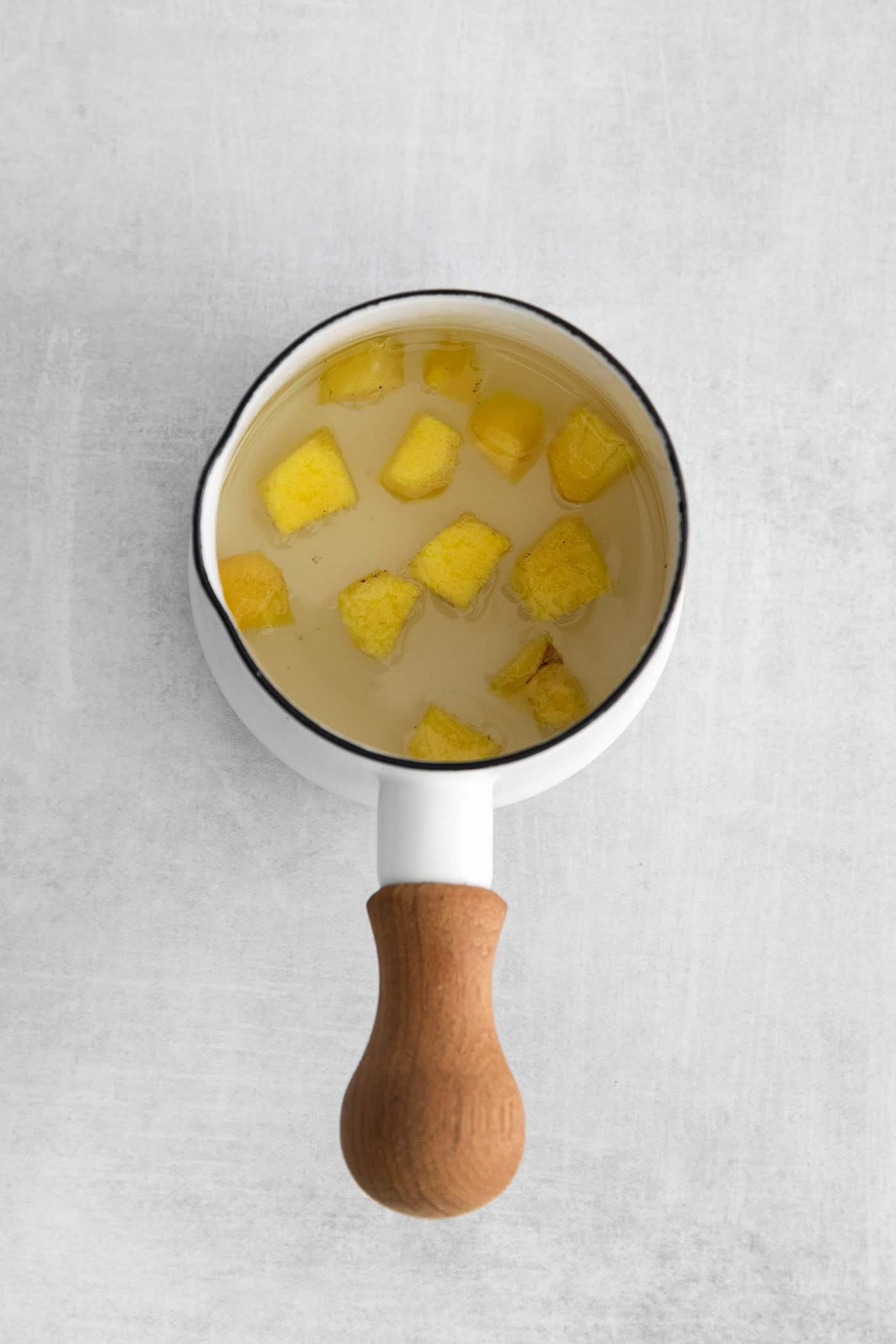 This Peach Mint Julep is bright, fresh, and fruity, with a hint of spice from fresh ginger. The perfect summer cocktail! Overhead view of ginger simple syrup in a saucepan