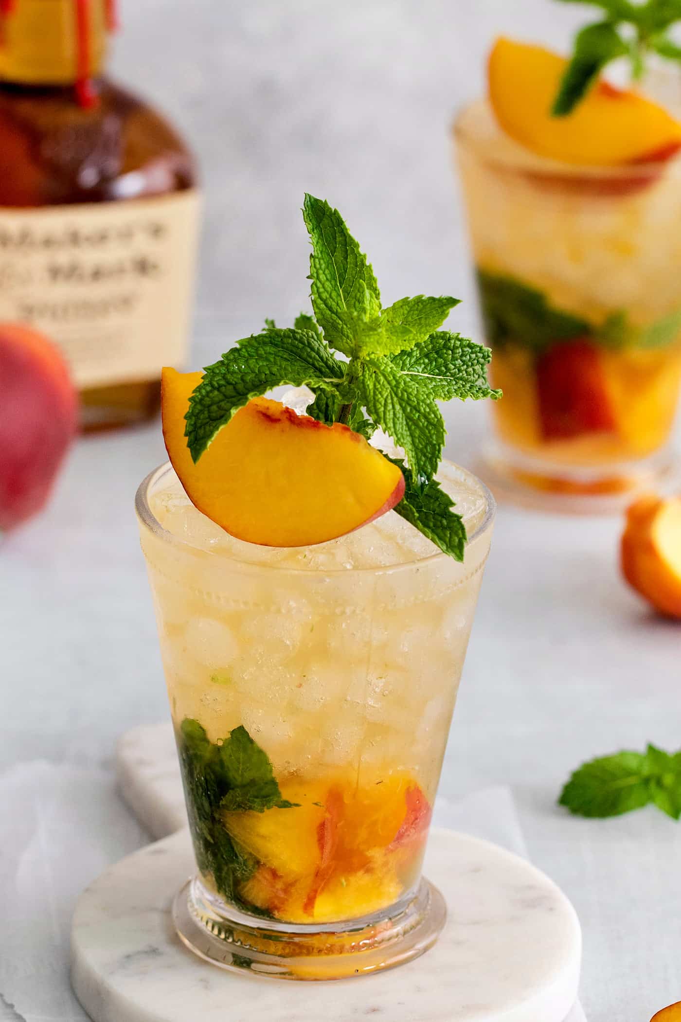 This Peach Mint Julep is bright, fresh, and fruity, with a hint of spice from fresh ginger. The perfect summer cocktail! Angled overhead view of a peach mint julep