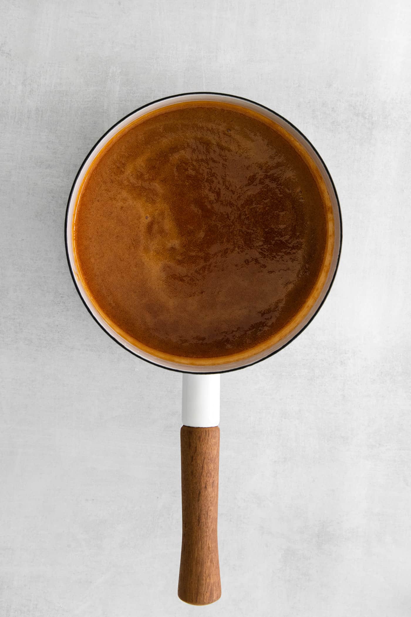 This Salted Caramel Ice Cream features a sweet and creamy ice cream base with homemade caramel sauce swirled throughout. Dark caramel in a sauce pan
