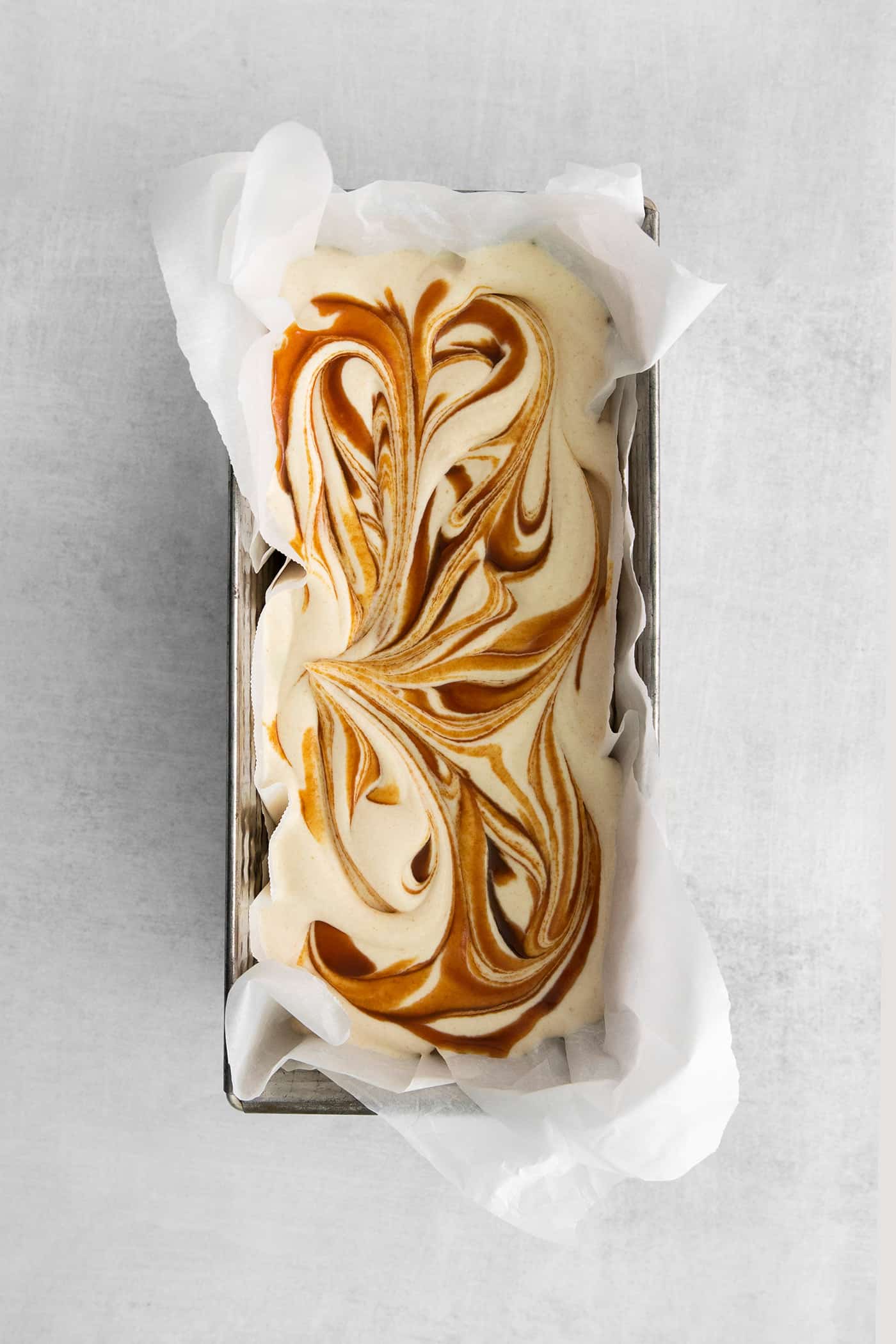 This Salted Caramel Ice Cream features a sweet and creamy ice cream base with homemade caramel sauce swirled throughout. Salted caramel ice cream in a loaf pan