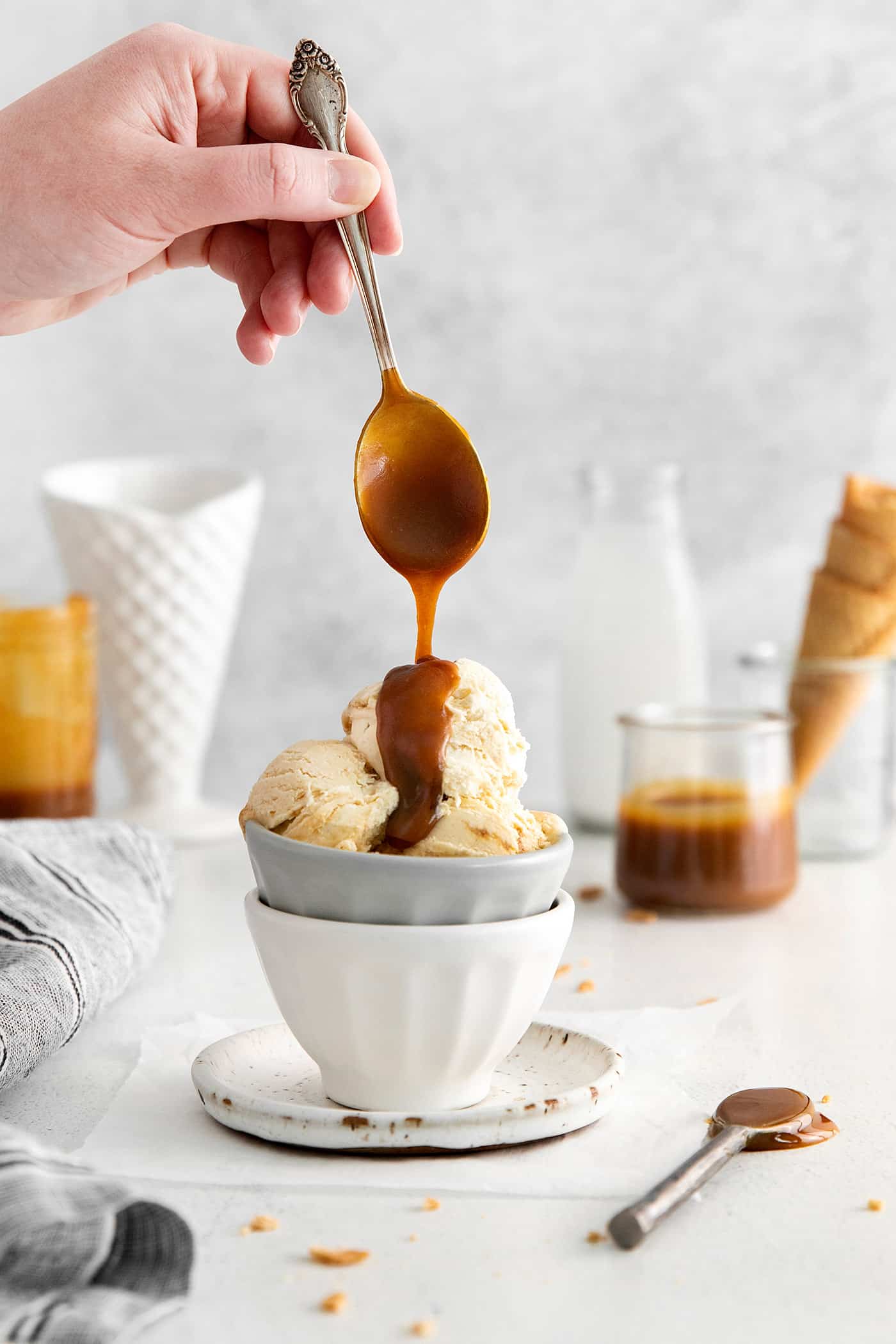 This Salted Caramel Ice Cream features a sweet and creamy ice cream base with homemade caramel sauce swirled throughout. A spoon drizzling caramel sauce of a bowl of ice cream