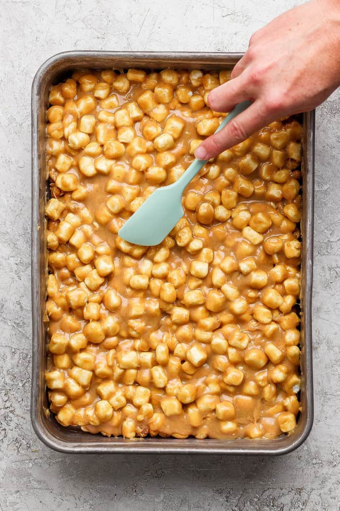 Salted Nut Roll Bars are the perfect salty and sweet combo, an easy riff on the classic candy bar. Just 5 ingredients and 15 minutes of prep! Spreading peanuts into caramel mixture.