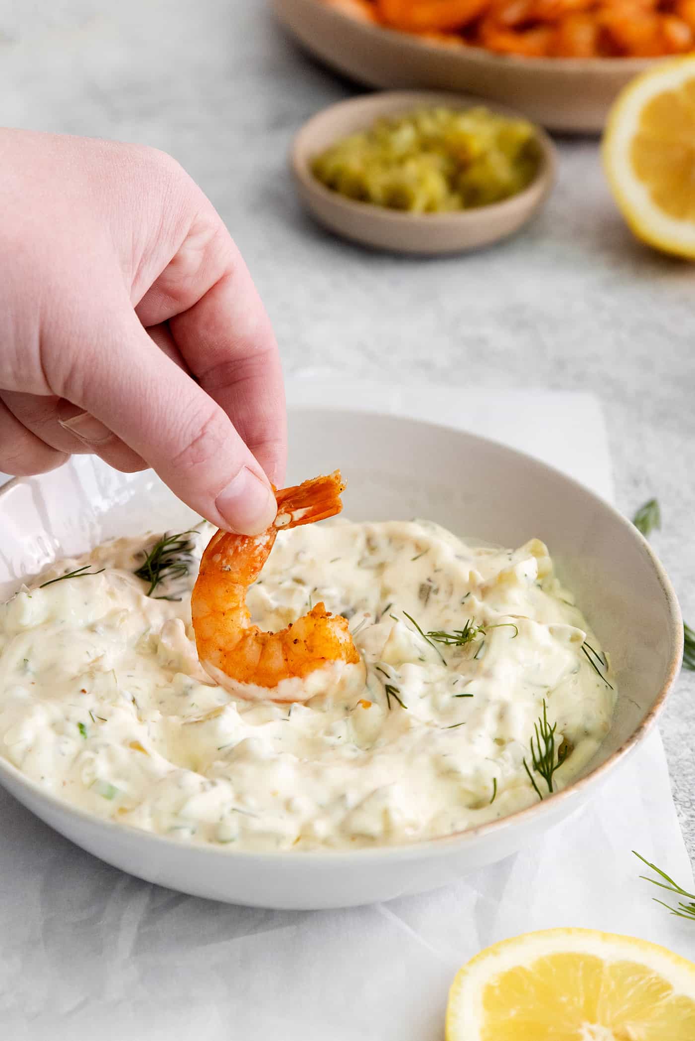 This Homemade Tartar Sauce is the perfect pairing for all your favorite seafood. Delightfully creamy with fresh dill and pickles. A hand dipping a shrimp into tartar sauce