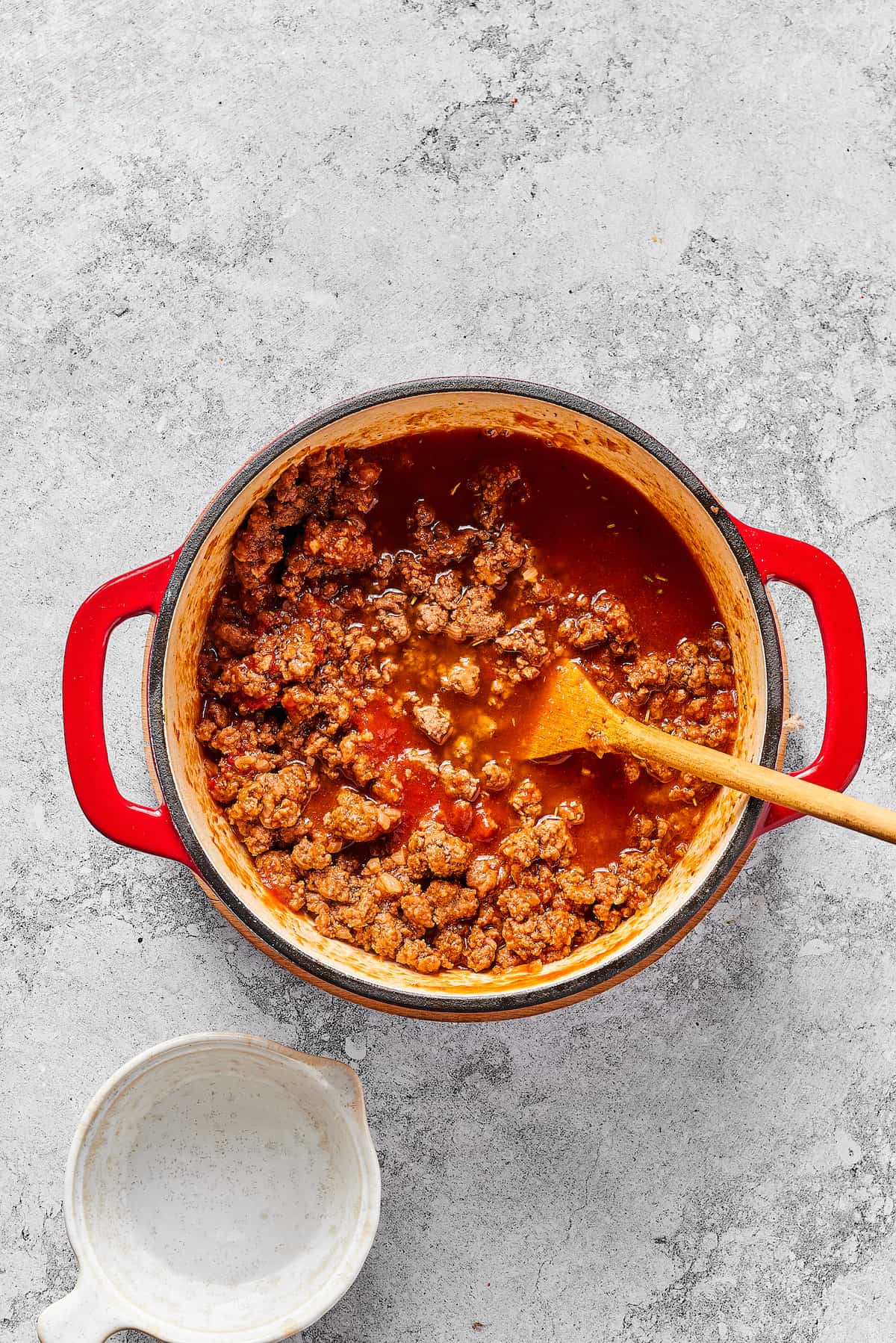 Made with tomato sauce, ground beef, and elbow macaroni, this Easy Beefaroni is the homemade version of the canned classic. Quick & easy! A wooden spoon stirring tomato sauce into ground beef