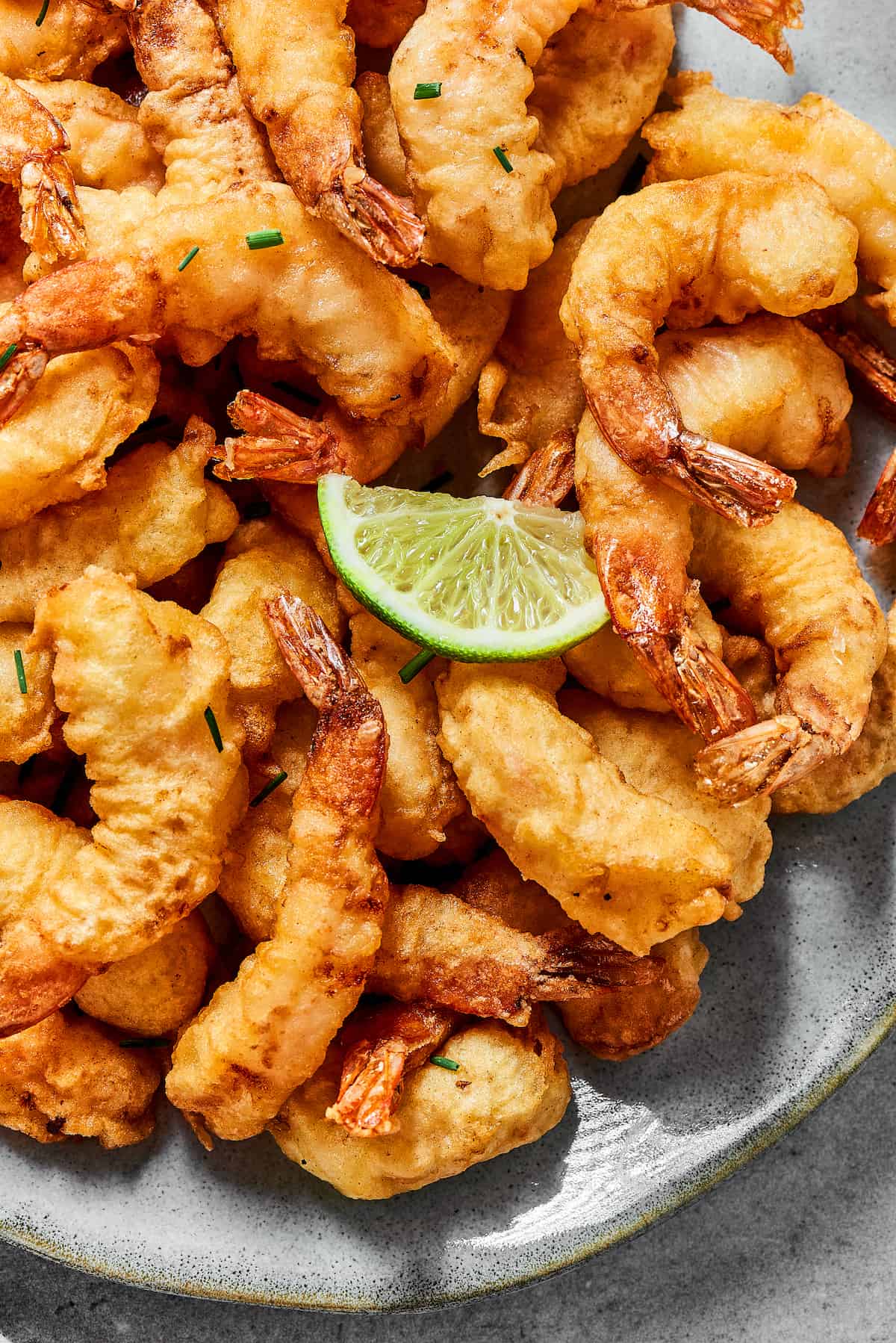 This easy shrimp tempura recipe features juicy, tender shrimp dipped in a light tempura batter. It's then deep-fried until perfectly crispy! A plate of shrimp tempura with a lime wedge