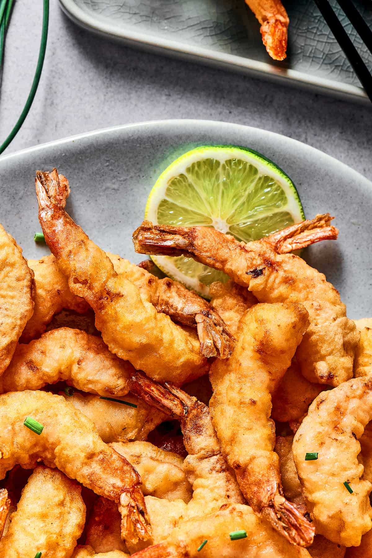 This easy shrimp tempura recipe features juicy, tender shrimp dipped in a light tempura batter. It's then deep-fried until perfectly crispy! A pile of tempura shrimp on a plate