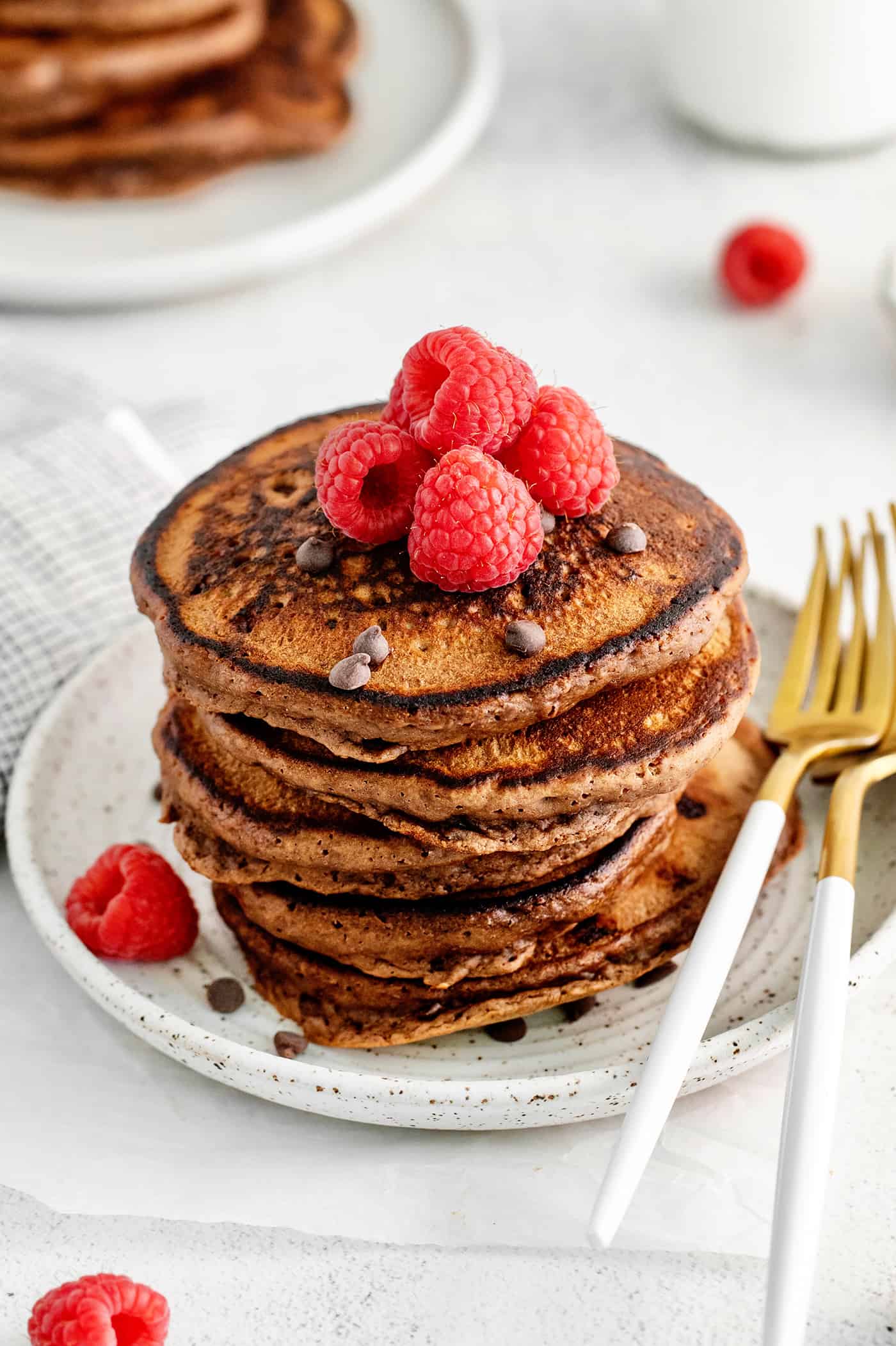 Fluffy, fudgy chocolate pancakes are rich in flavor with pockets of melty chocolate chips throughout. The real chocolate lover's breakfast! A tall stack of chocolate pancakes topped with raspberries