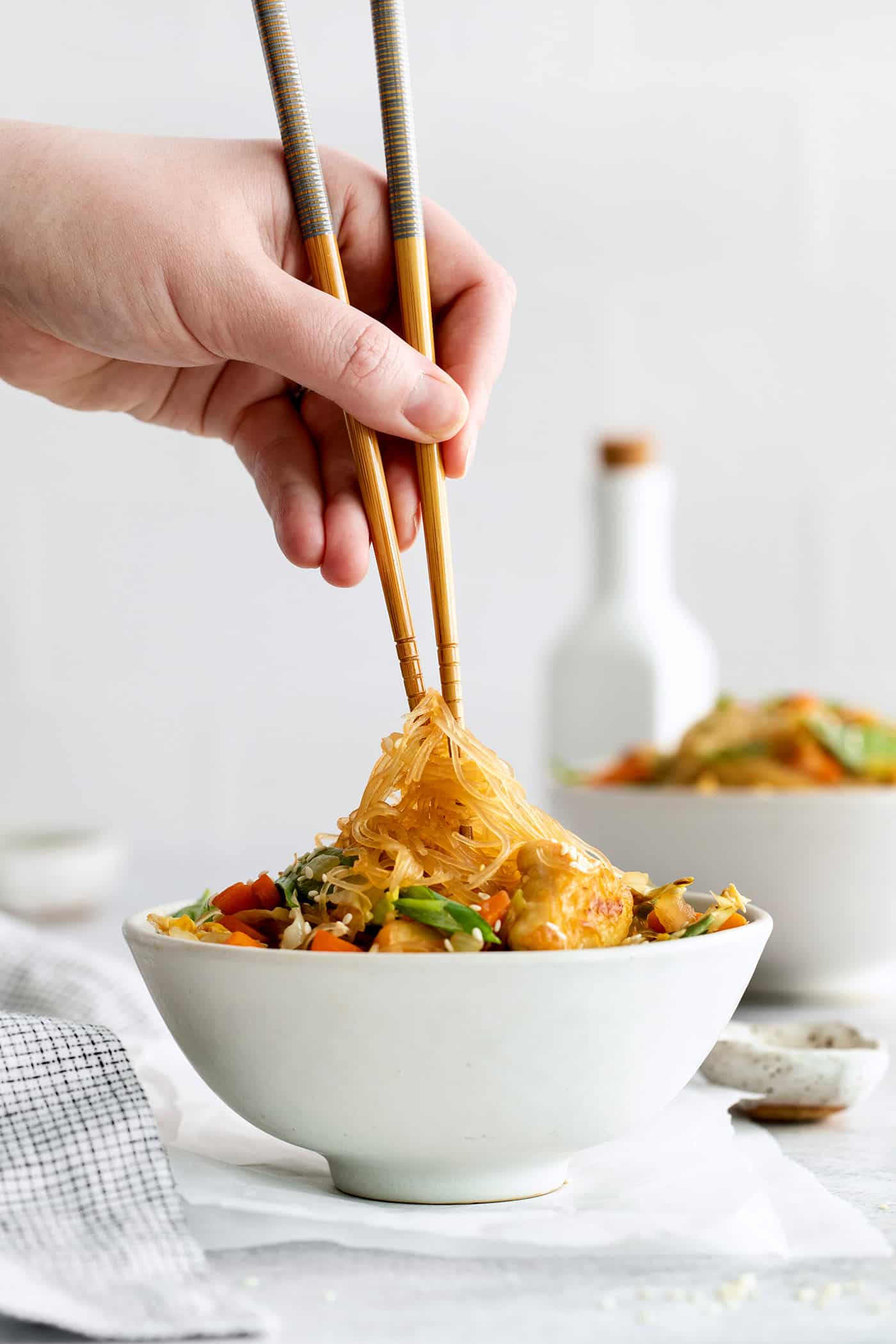 Made with glass noodles, mixed vegetables, and a savory soy glaze, Pad Woon Sen is an easy Thai stir fry that's ready in just 30 minutes! A hand holding chopsticks with glass noodles