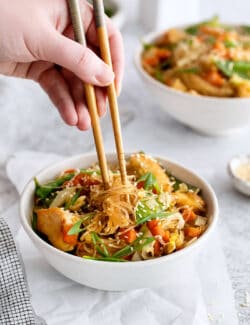 A hand holding chopsticks above pad woon sen