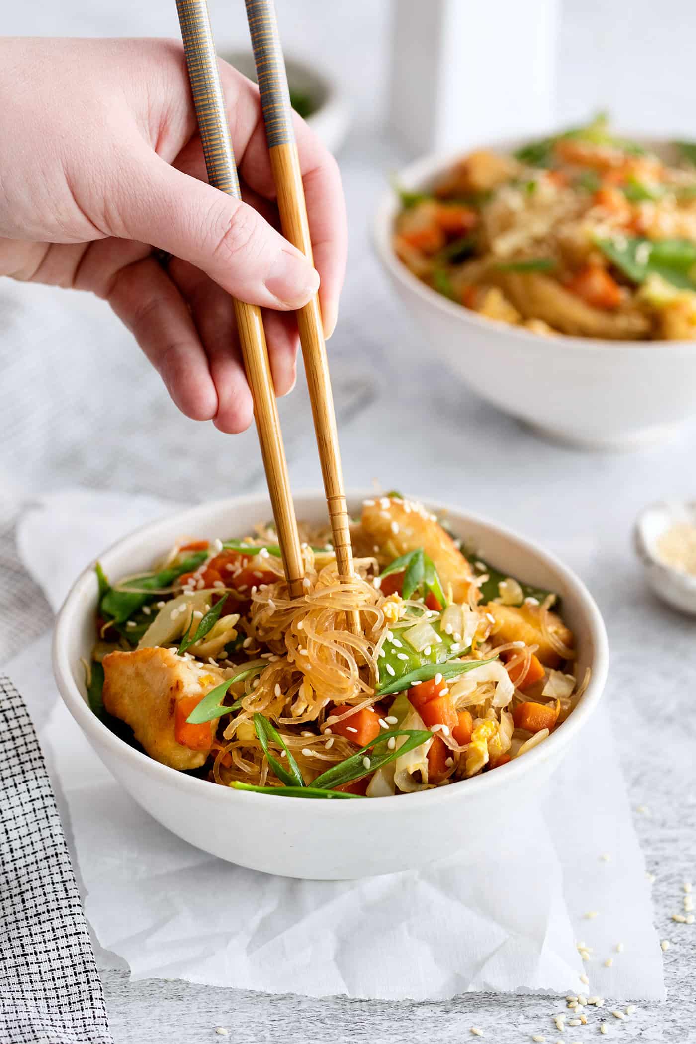 Made with glass noodles, mixed vegetables, and a savory soy glaze, Pad Woon Sen is an easy Thai stir fry that's ready in just 30 minutes! A hand holding chopsticks above pad woon sen