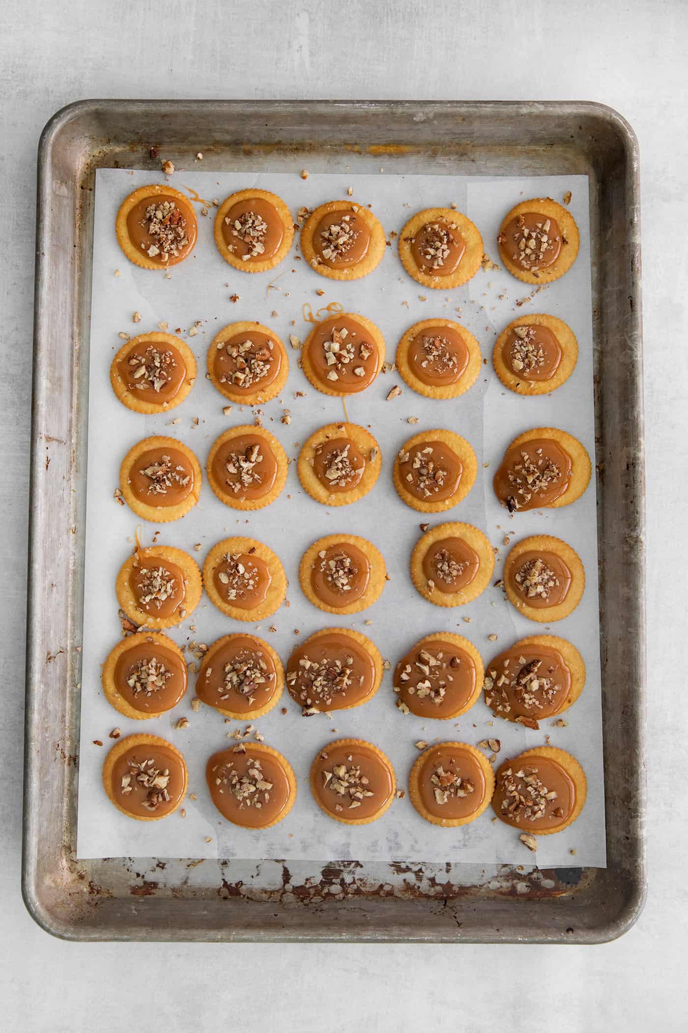 Made with 6 ingredients, Ritz Turtles are a fun, easy treat. These Ritz cracker caramel cookies are sweet, salty, crunchy & chewy all in one. Ritz crackers topped with caramel on a baking sheet
