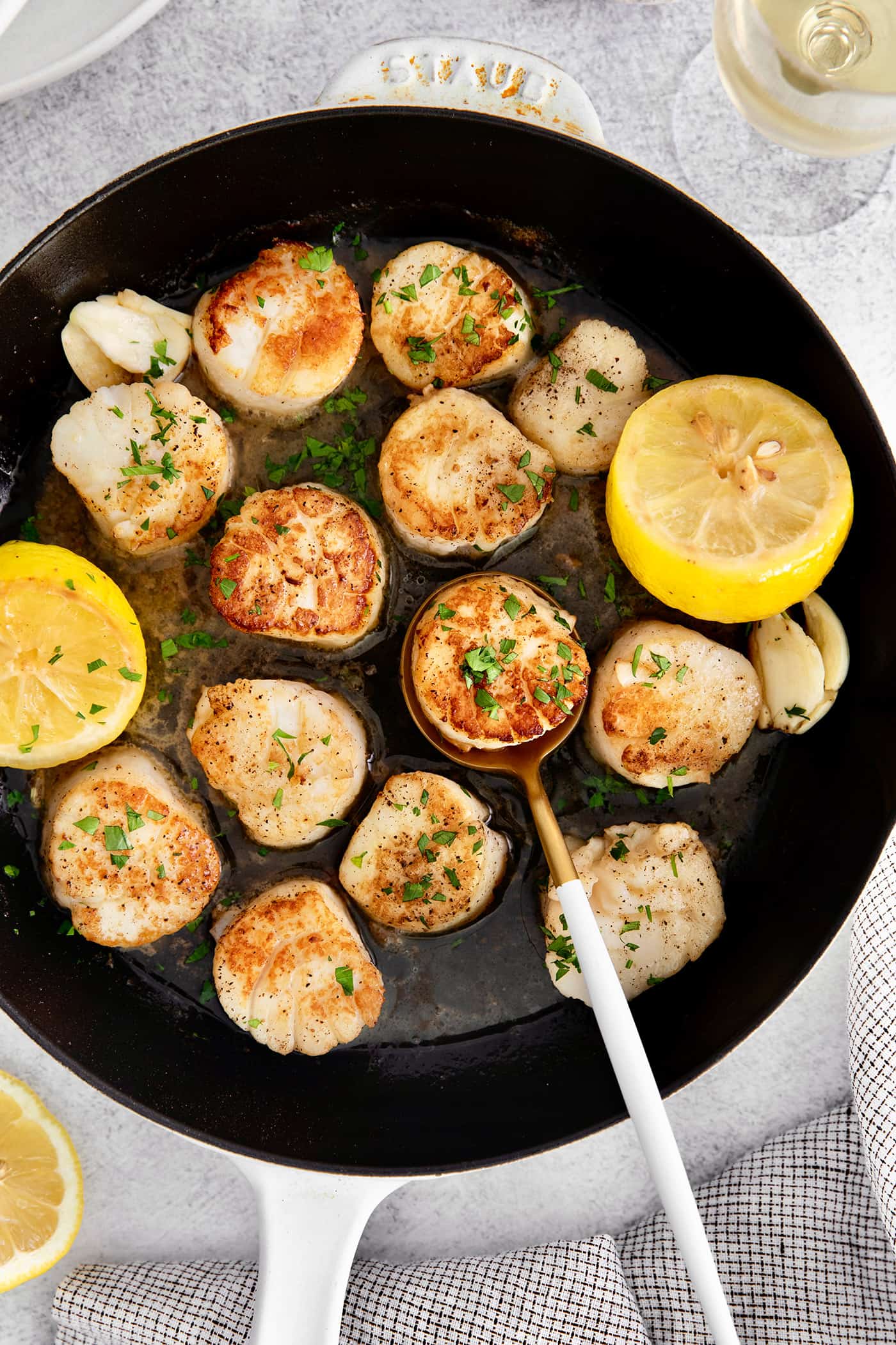 Made with a simple lemon garlic butter sauce, these Pan Seared Scallops are guaranteed to be the highlight of any dinner. Overhead view of seared scallops in a skillet