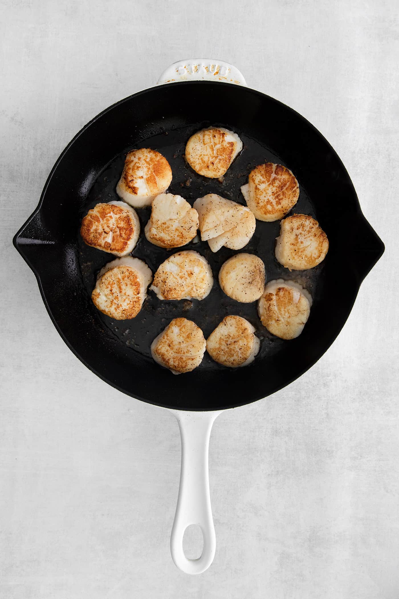 Made with a simple lemon garlic butter sauce, these Pan Seared Scallops are guaranteed to be the highlight of any dinner. Overhead view of scallops in a skillet
