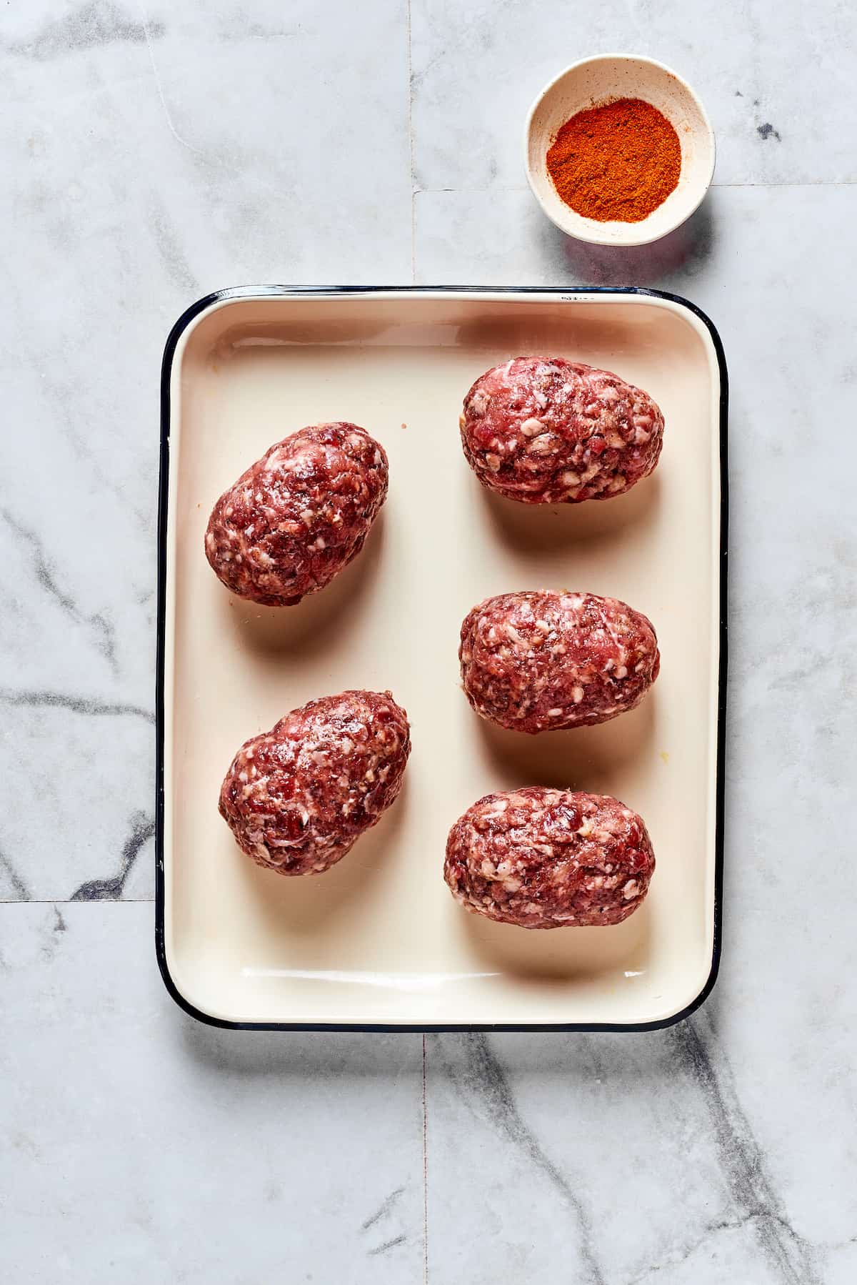If you love jalapeno poppers, you are going to LOVE these Armadillo Eggs - cheese-stuffed jalapenos wrapped in bacon and sausage. Yum! Jalapeno poppers wrapped in sausage on a baking sheet