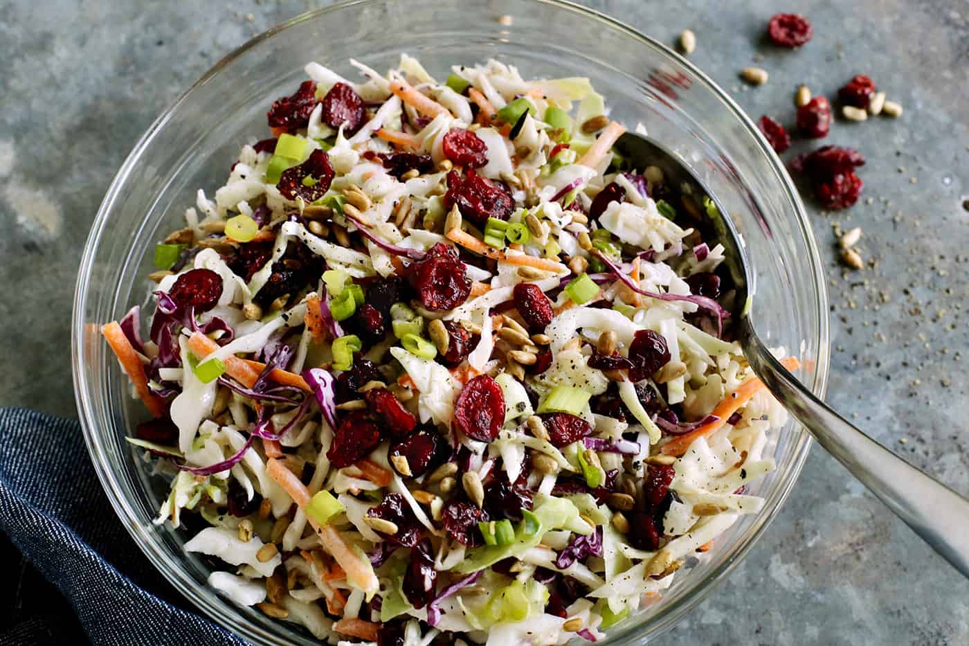 Made with a creamy, tangy dressing, dried cranberries, and sunflower kernels, this Cranberry Coleslaw is an easy side for any occasion. Overhead view of a bowl of cranberry coleslaw