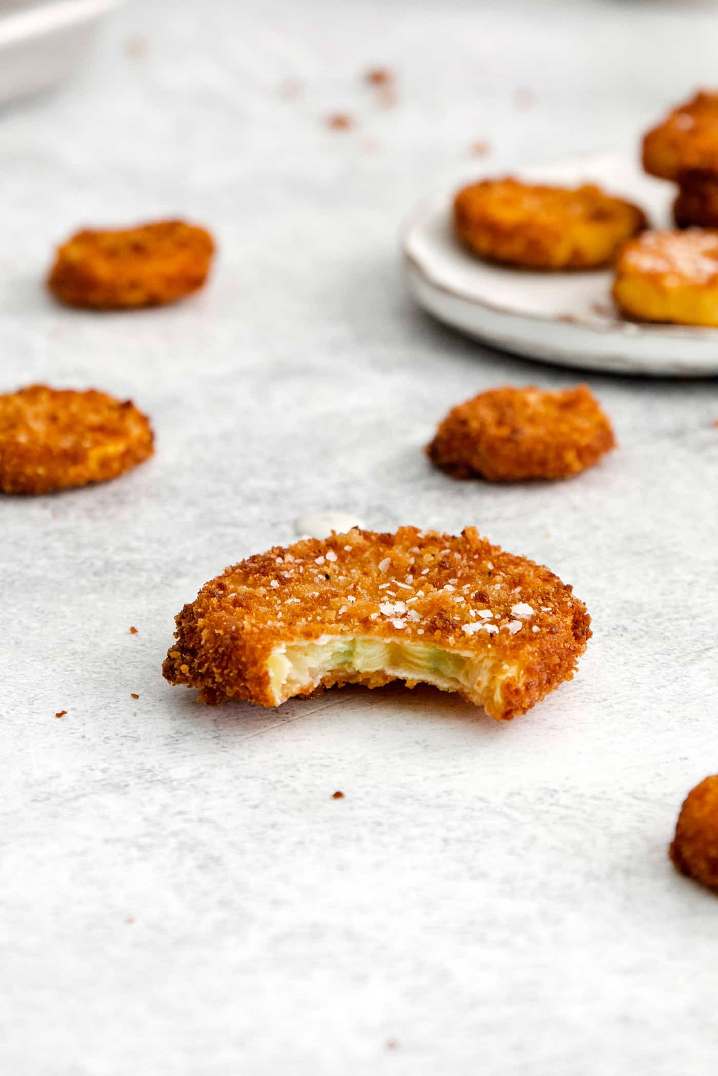 This easy, flavorful fried yellow squash is delightfully crispy on the outside and tender on the inside. Grab your favorite dip and enjoy! A fried squash round with a bite missing