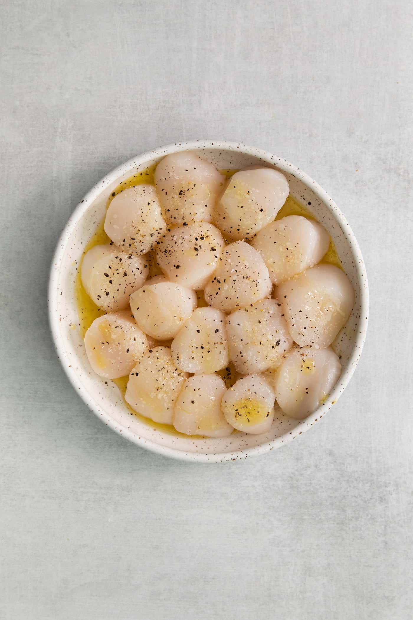 These easy grilled sea scallops are done in 20 minutes and richly flavored with garlic butter and lemon. Cook on an indoor or outdoor grill! Scallops in a bowl with butter, salt, and pepper