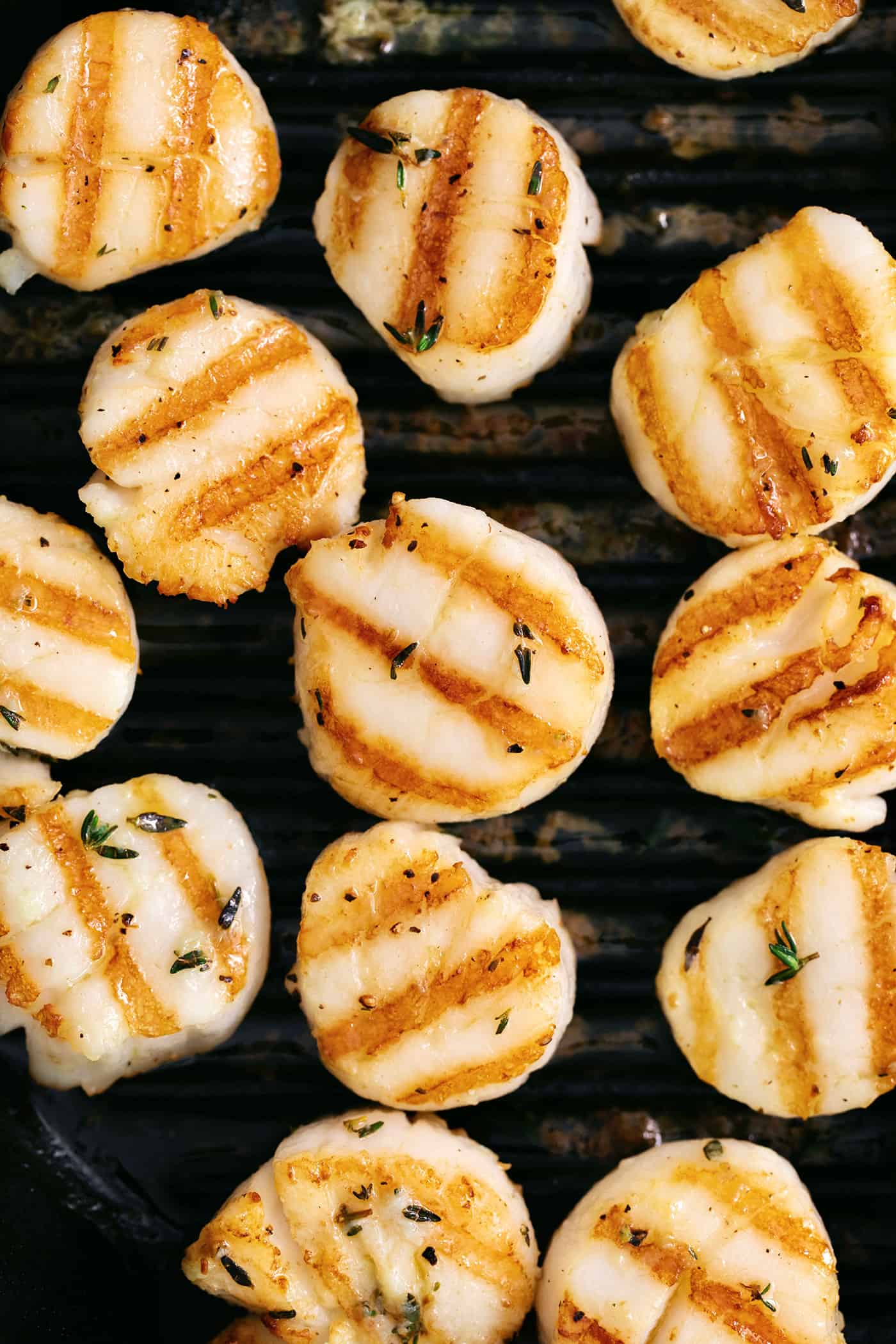 These easy grilled sea scallops are done in 20 minutes and richly flavored with garlic butter and lemon. Cook on an indoor or outdoor grill! Overhead view of grilled scallops