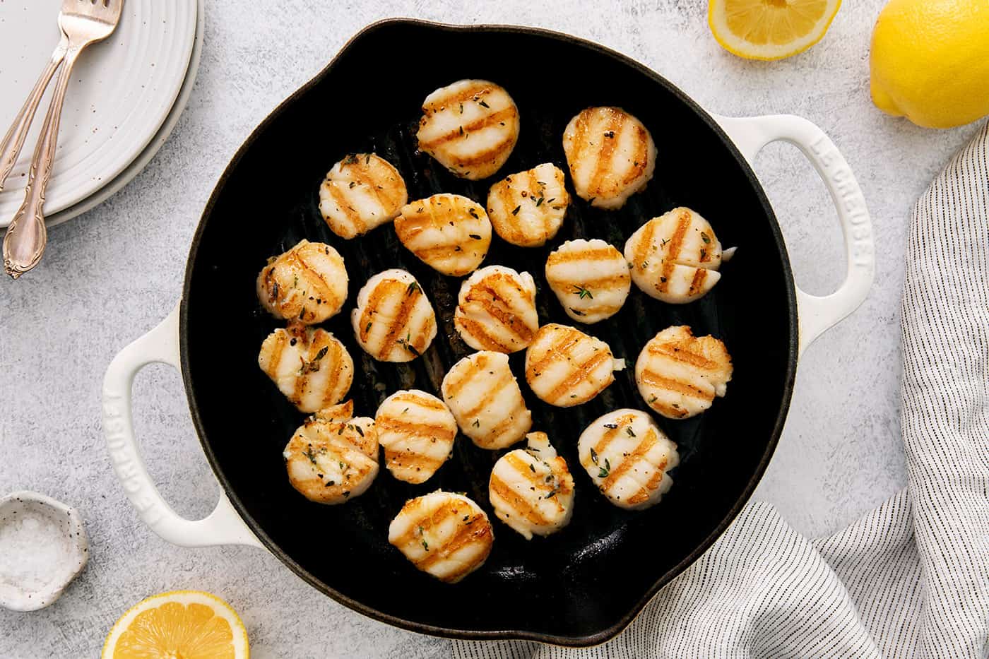 These easy grilled sea scallops are done in 20 minutes and richly flavored with garlic butter and lemon. Cook on an indoor or outdoor grill! a grill pan with scallops in it