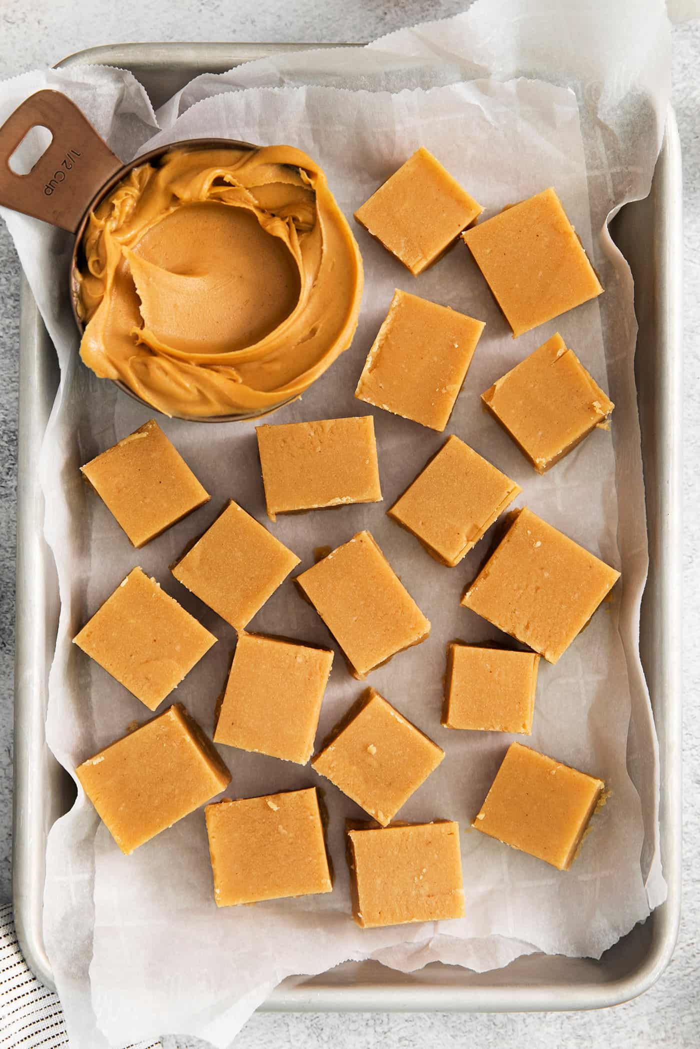Made with 7 ingredients, this Homemade Peanut Butter Fudge is rich, creamy, and easy to make. It's the perfect fudge for the holidays! Overhead view of pieces of peanut butter fudge