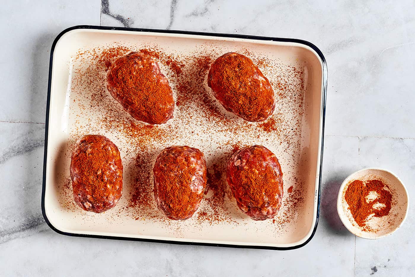 sprinkling paprika over the sausage