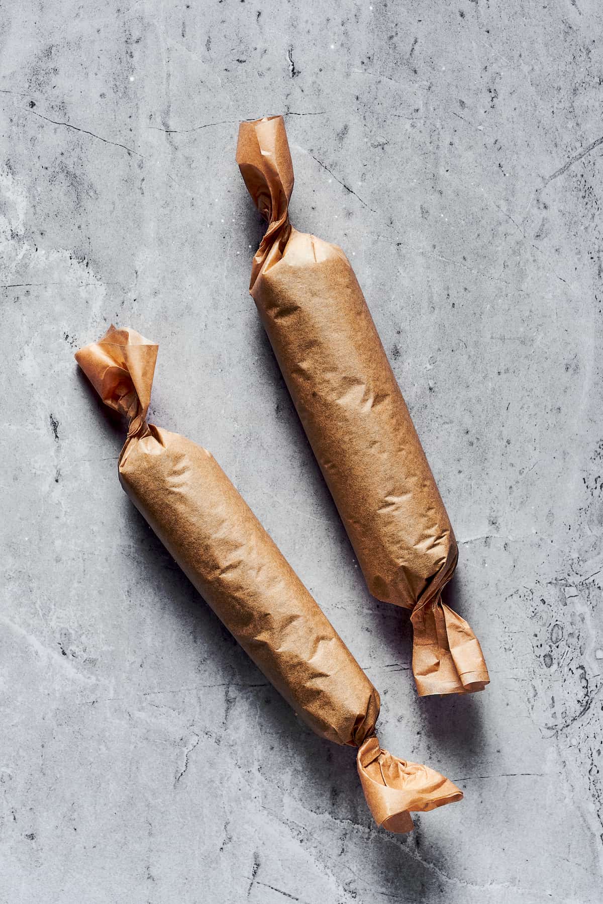 This Sushi Burrito recipe results in a giant sushi roll stuffed with spicy salmon, rice, avocado, carrots, and other veggies. Two sushi burritos wrapped in brown paper