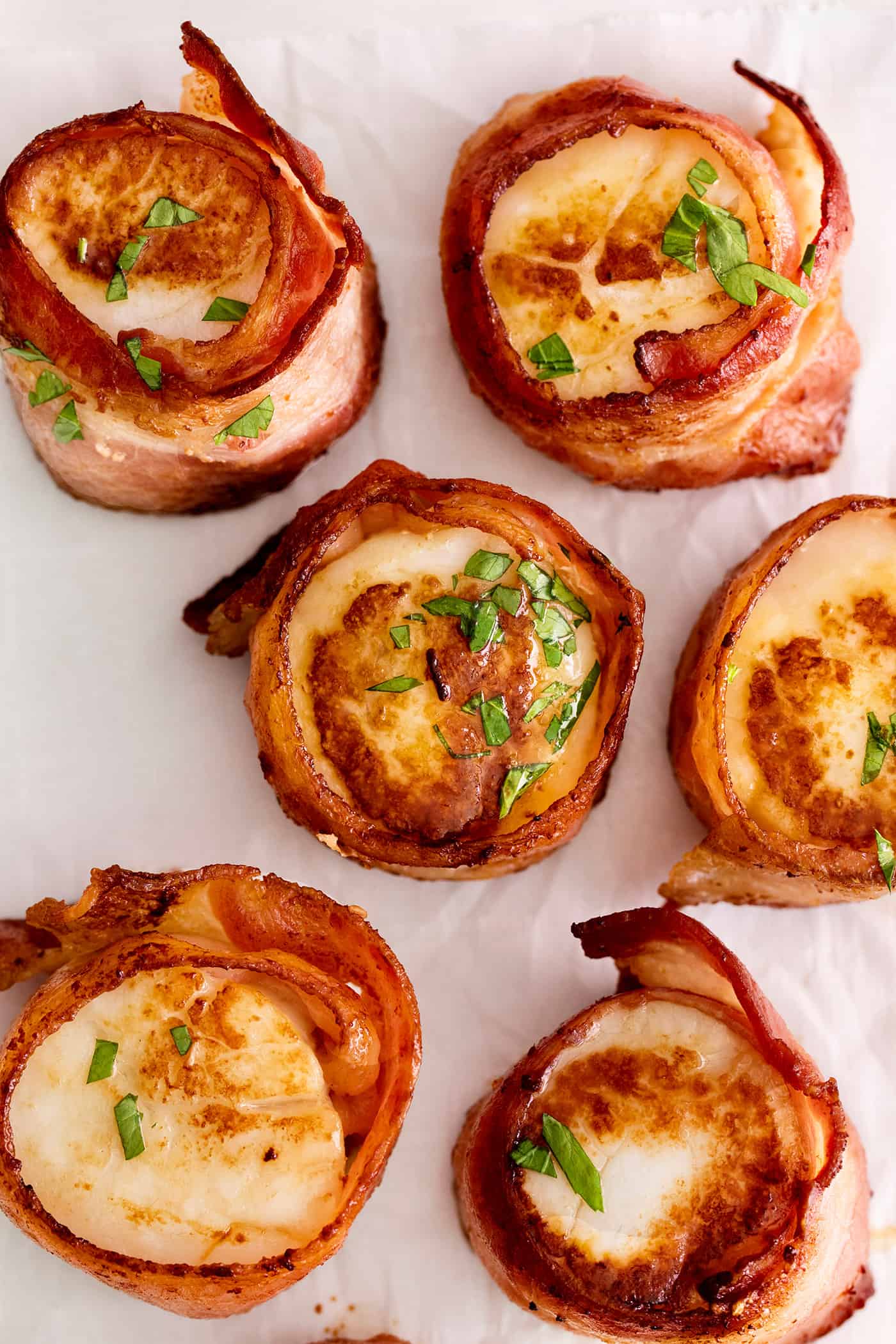 These Bacon Wrapped Scallops are tender and juicy, surrounded by crisp bacon, and topped with a delicious garlic butter. Overhead view of bacon wrapped scallops