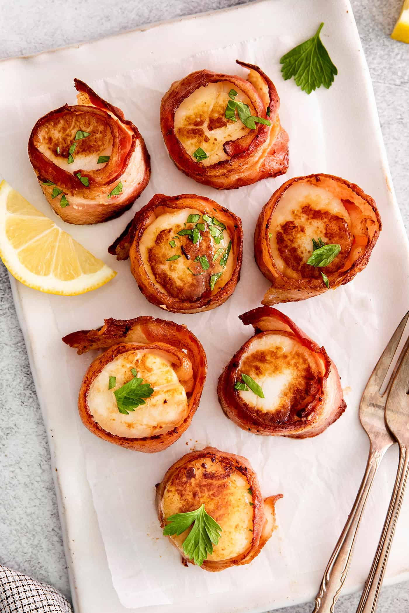 These Bacon Wrapped Scallops are tender and juicy, surrounded by crisp bacon, and topped with a delicious garlic butter. Overhead view of bacon wrapped scallops