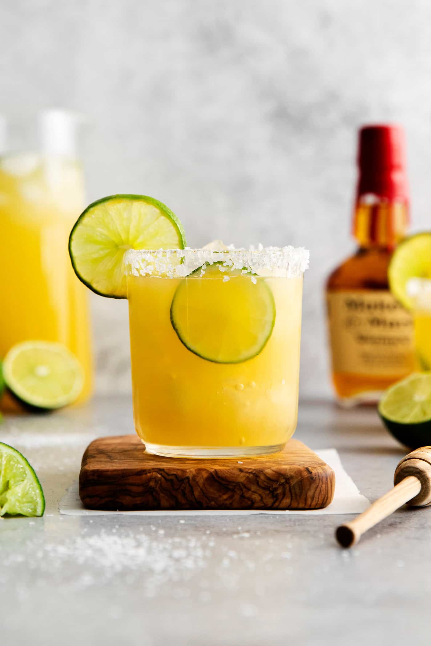 This Bourbon Margarita is a riff on a classic margarita, where bourbon replaces tequila. If you enjoy a whiskey sours, you’ll love this! A bourbon margarita on a wooden coaster