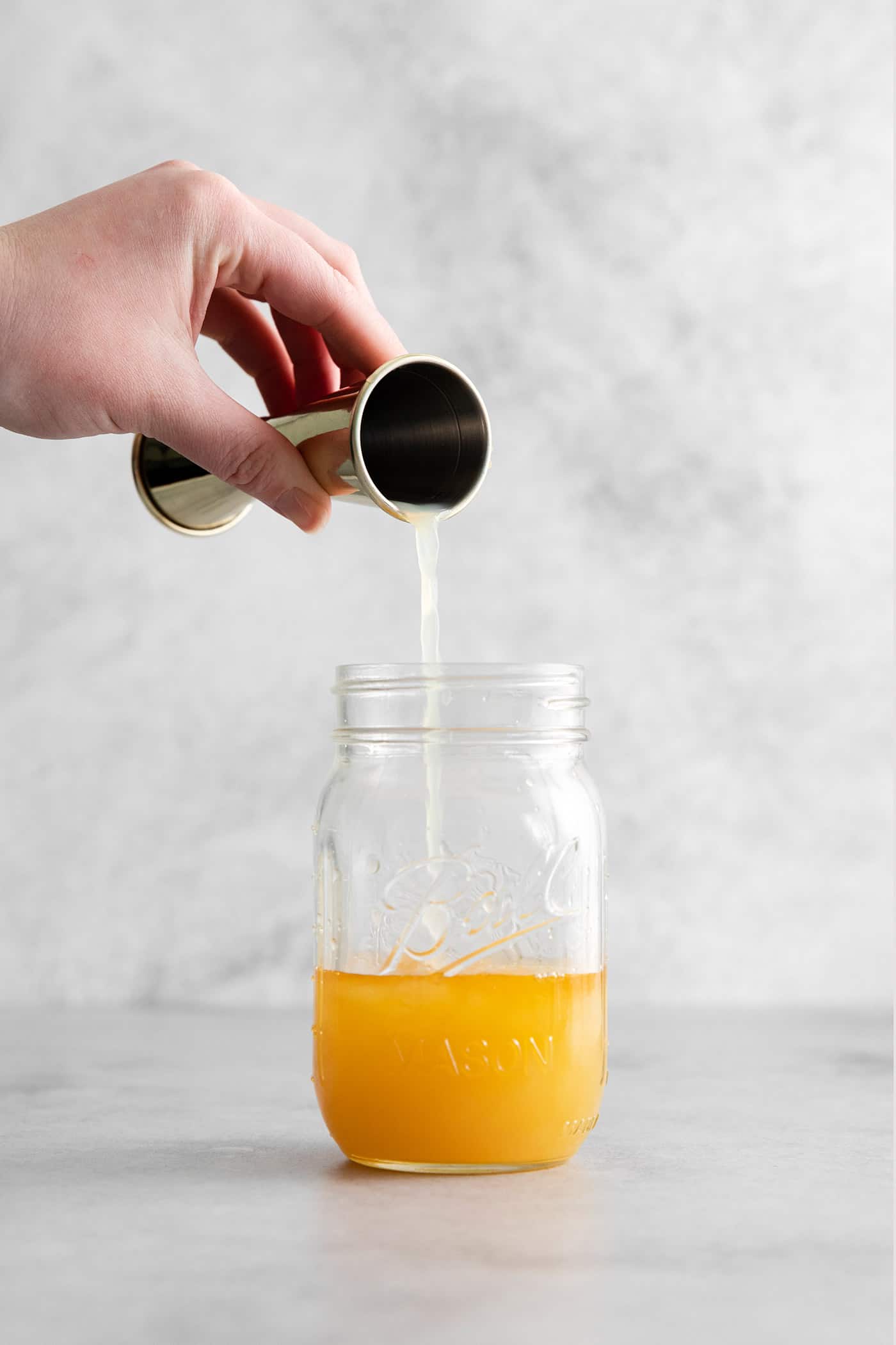This Bourbon Margarita is a riff on a classic margarita, where bourbon replaces tequila. If you enjoy a whiskey sours, you’ll love this! A hand pouring bourbon into a mason jar
