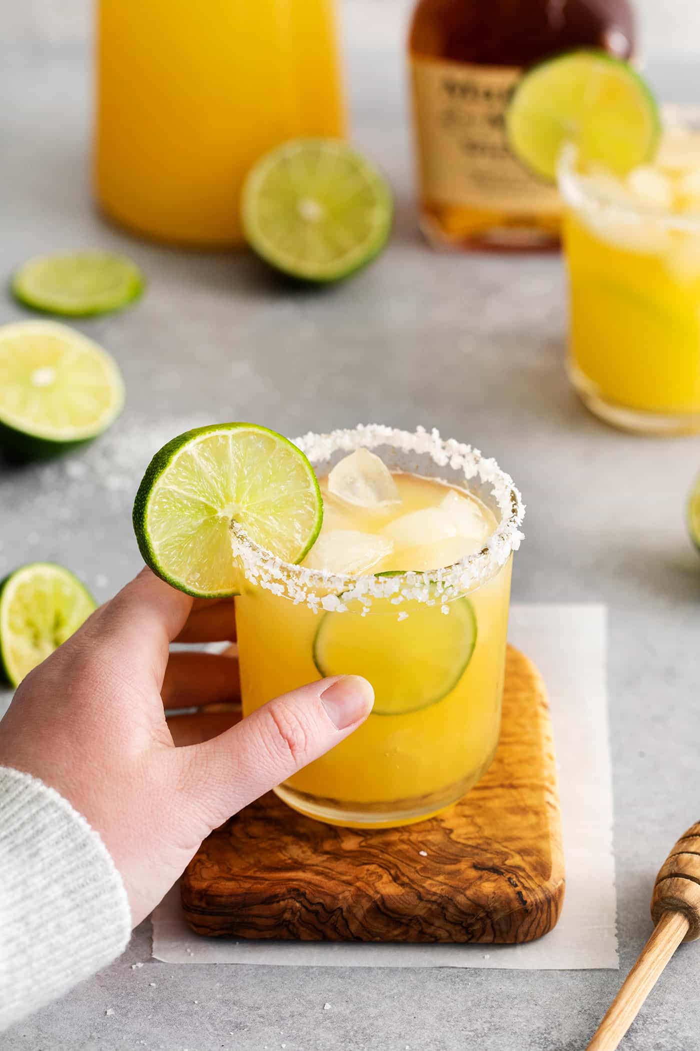 This Bourbon Margarita is a riff on a classic margarita, where bourbon replaces tequila. If you enjoy a whiskey sours, you’ll love this! A hand reaching for a whiskey margarita