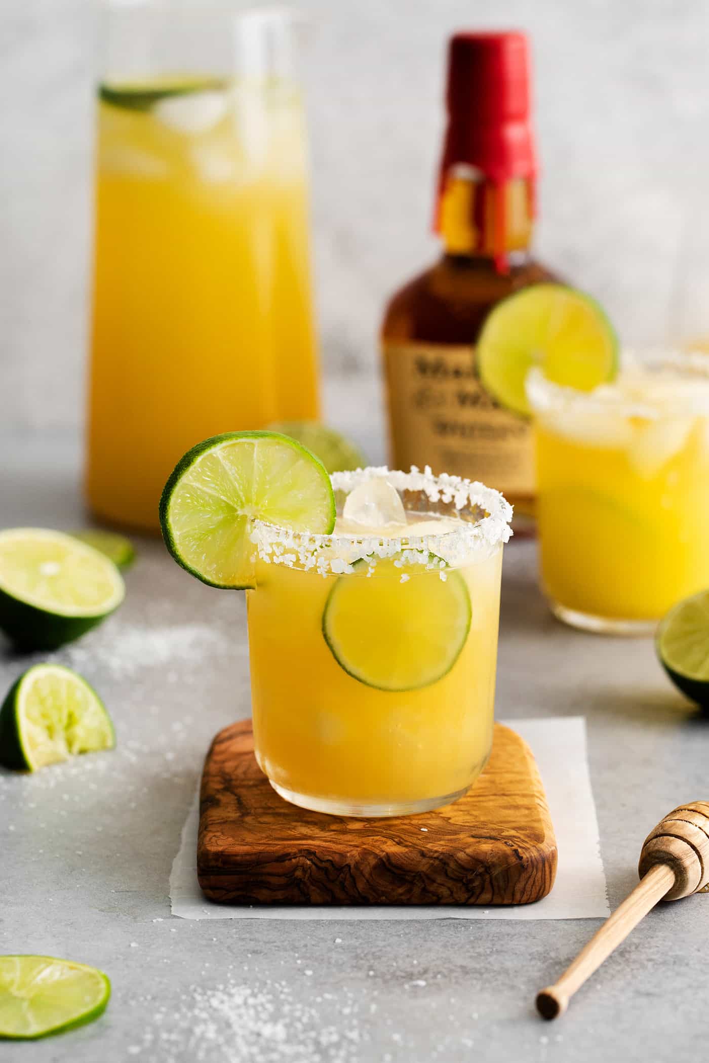 This Bourbon Margarita is a riff on a classic margarita, where bourbon replaces tequila. If you enjoy a whiskey sours, you’ll love this! A bourbon margarita on a wooden coaster