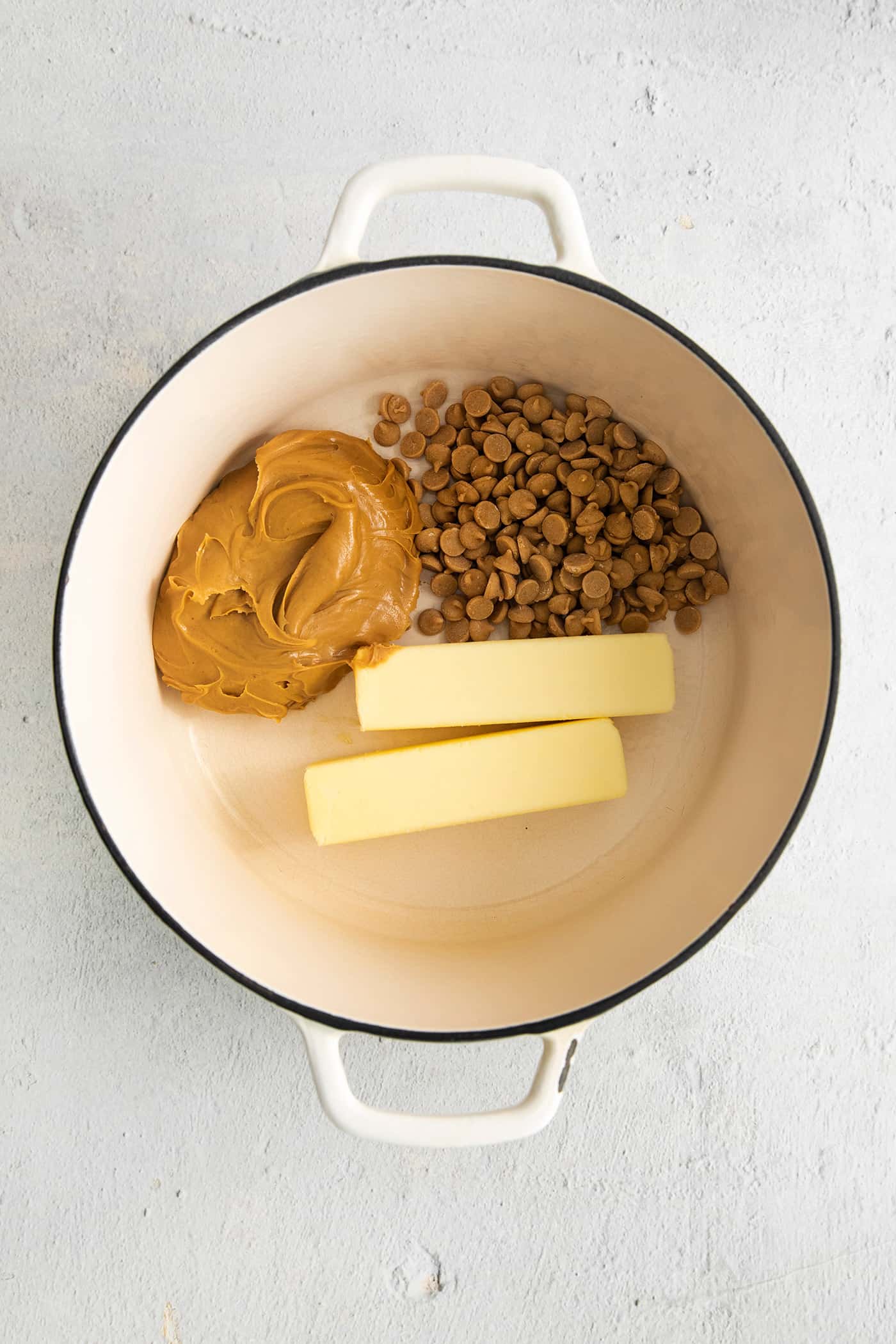 This Buckeye Fudge is a fun twist on traditional buckeyes, with smooth, creamy peanut butter fudge topped with a layer of rich chocolate. Peanut butter, butter, and peanut butter chips in a saucepan