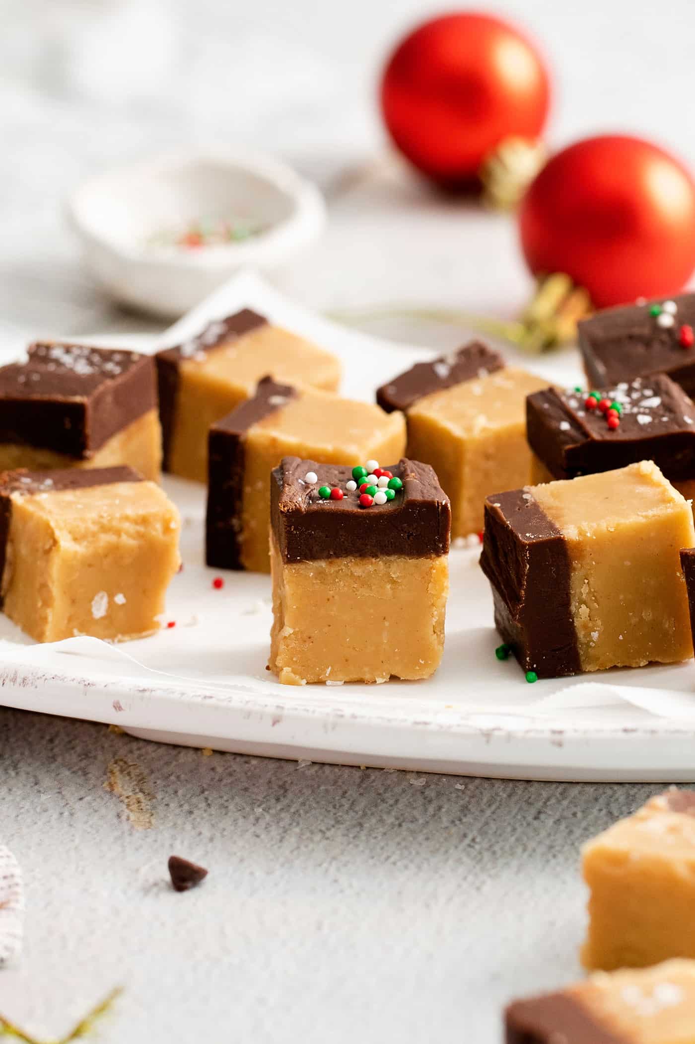 This Buckeye Fudge is a fun twist on traditional buckeyes, with smooth, creamy peanut butter fudge topped with a layer of rich chocolate. Pieces of buckeye fudge with Christmas sprinkles