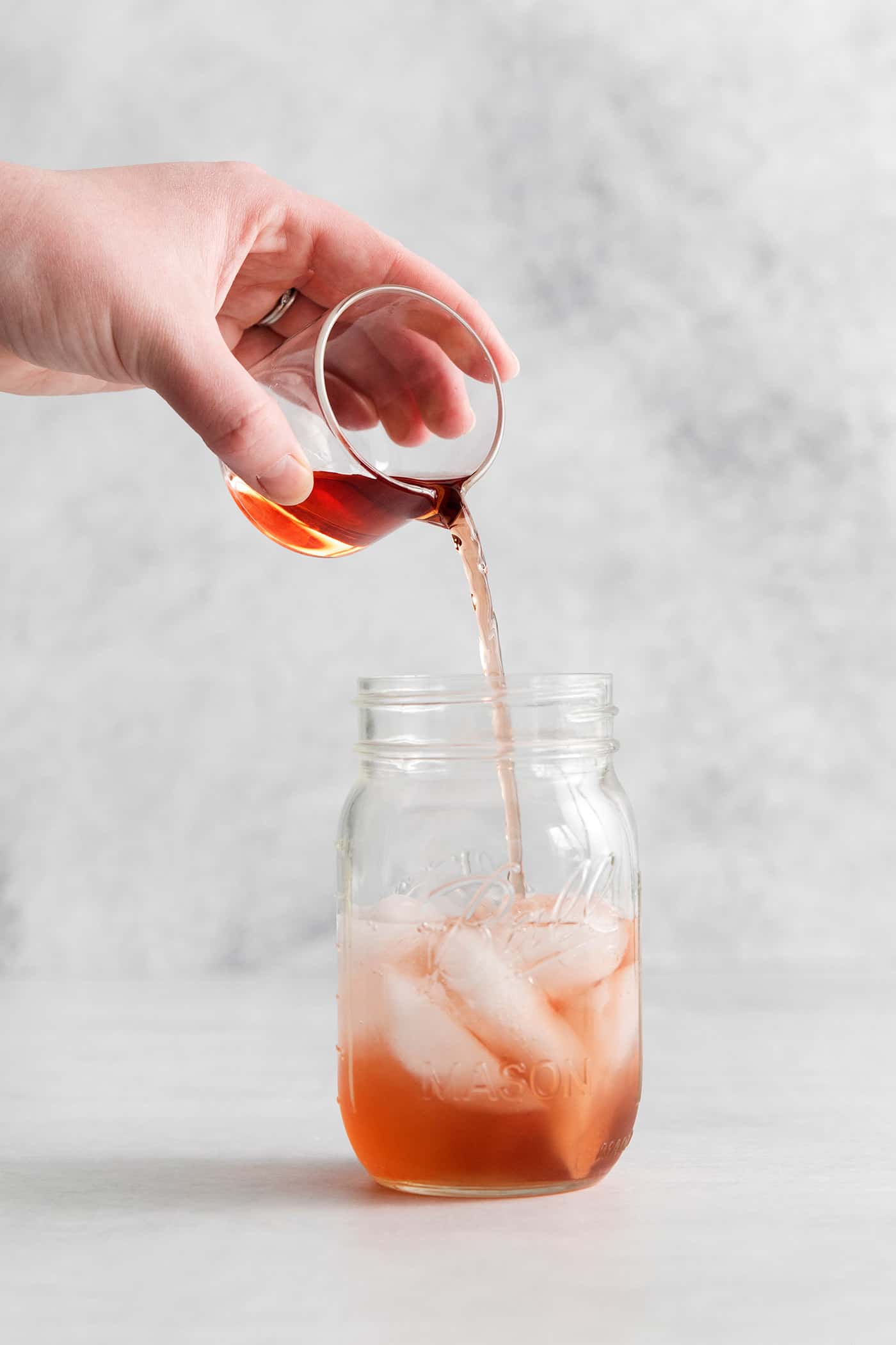 This Cranberry Margarita is tart and refreshing with flavors of cranberry and lime. A great Christmas margarita option! A hand pouring cranberry juice into a mason jar