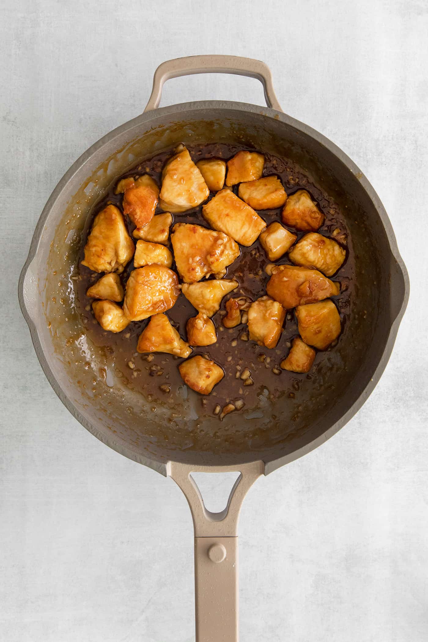 These Honey Garlic Chicken Bowls are quick and easy with moist chunks of chicken tossed in a sweet and sticky garlic sauce. Cooked pieces of chicken in a cast iron skillet