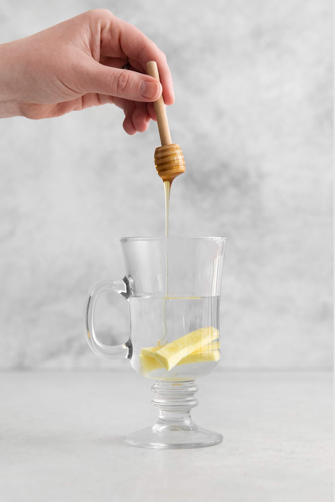 This Hot Toddy is the perfect winter drink! It’s warm and cozy with a hint of earthy honey, spicy ginger, and a burst of lemon. Honey being drizzled into a mug with hot water and ginger