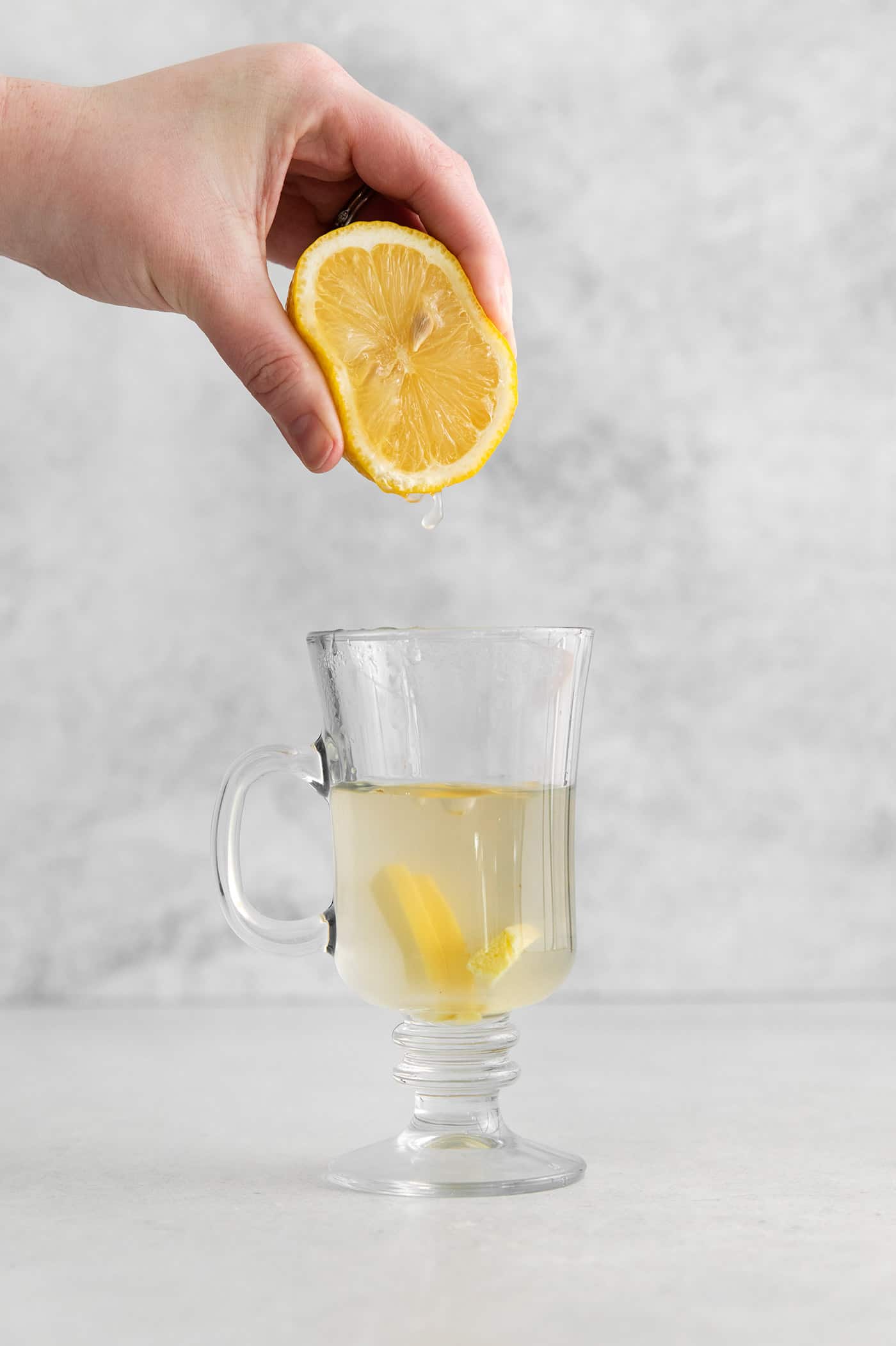 This Hot Toddy is the perfect winter drink! It’s warm and cozy with a hint of earthy honey, spicy ginger, and a burst of lemon. Lemon being squeezed into a mug of hot water and honey