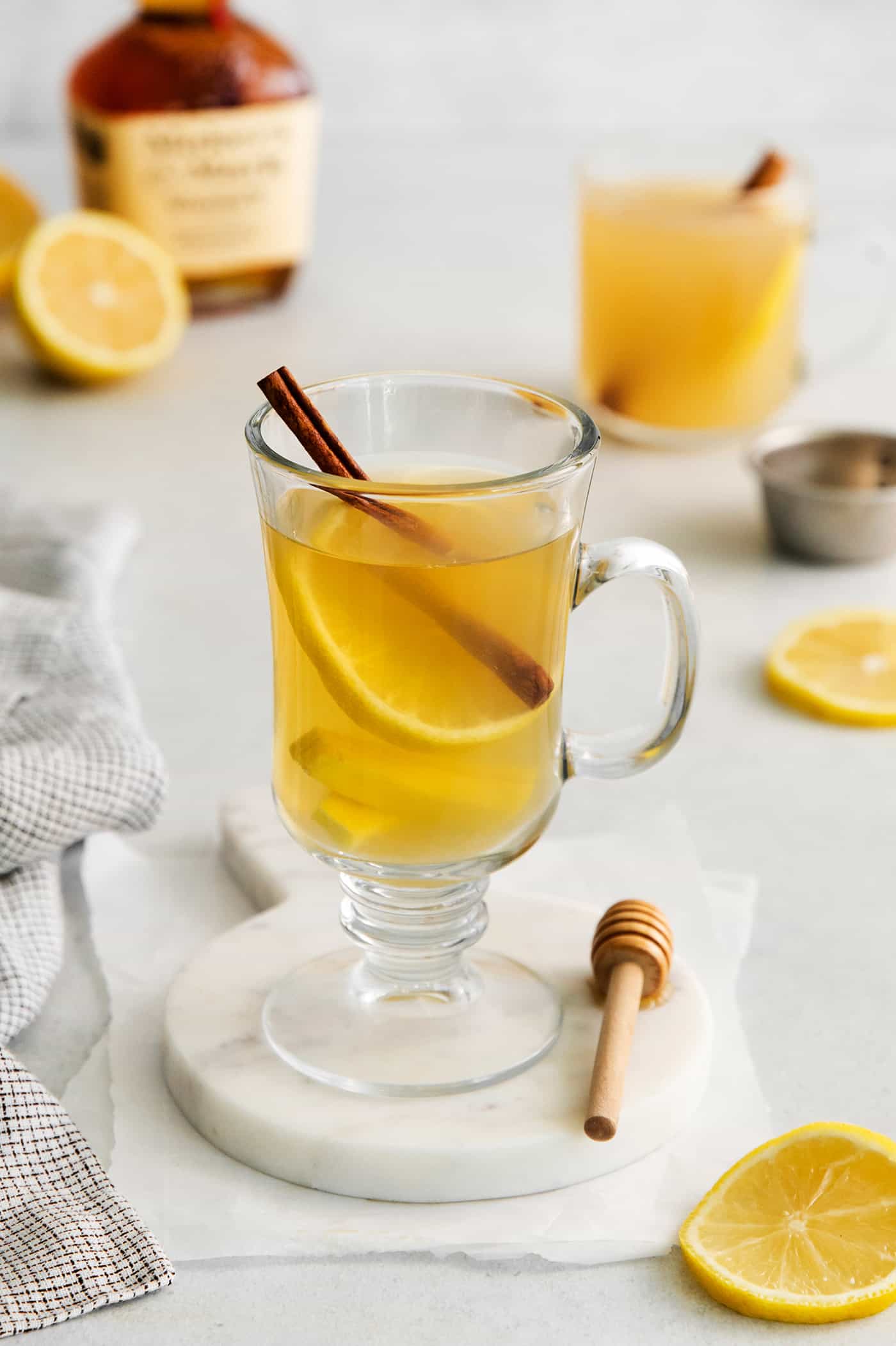 This Hot Toddy is the perfect winter drink! It’s warm and cozy with a hint of earthy honey, spicy ginger, and a burst of lemon. A hot tottie on a white coaster