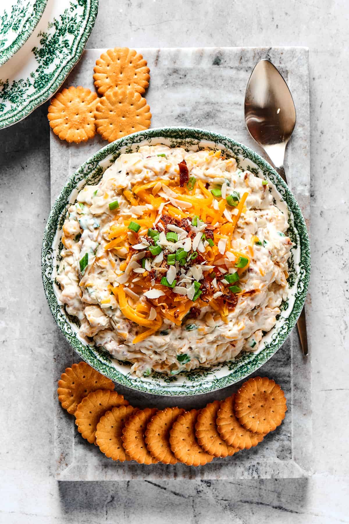 Million Dollar Dip is creamy, cheesy, and super easy to make. With cheese, bacon, and almonds, it's a super addicting party dip. Overhead view of a bowl of Neiman Marcus dip with Ritz crackers