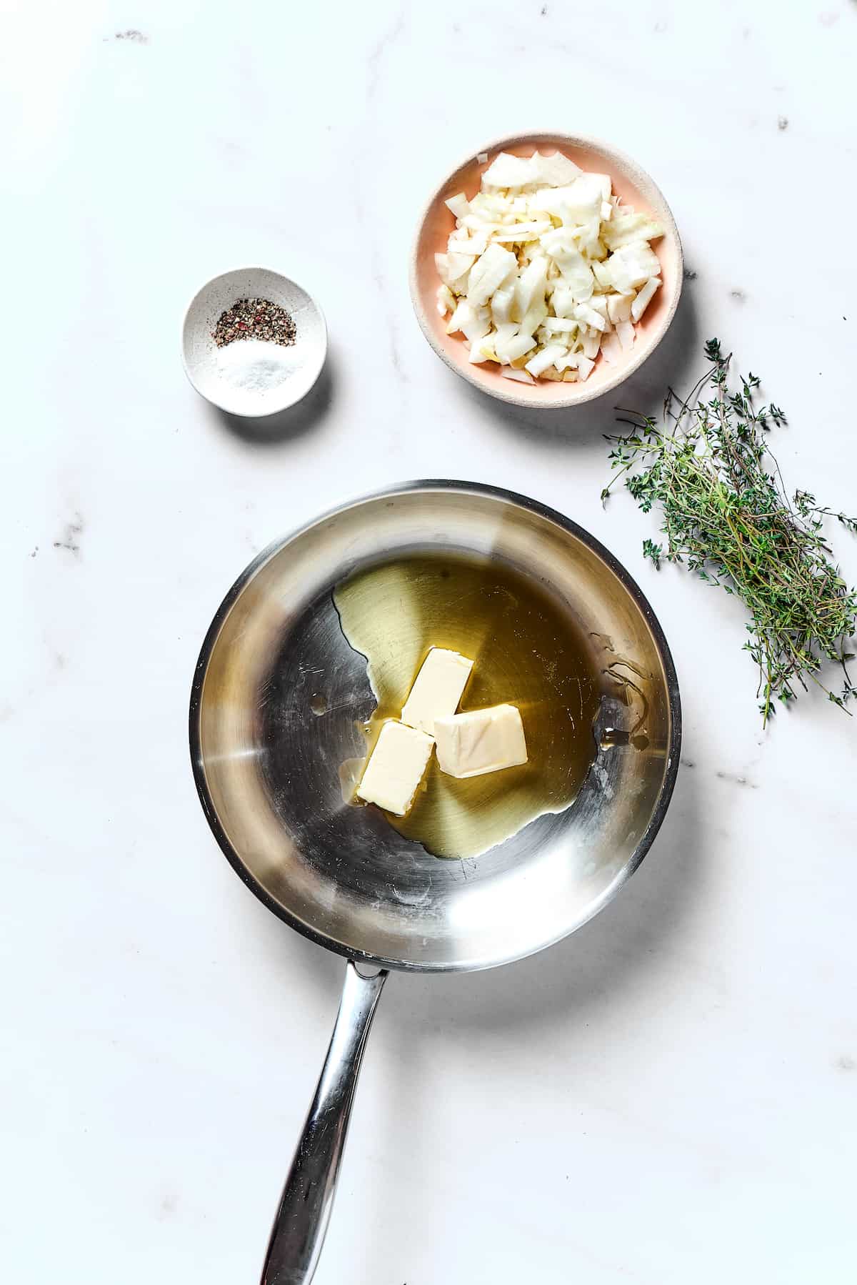 Potato Knishes are a popular Jewish recipe featuring a mashed potato and onion filling wrapped in a thin, flaky dough and baked to golden. Overhead view of butter melting in a pan with olive oil